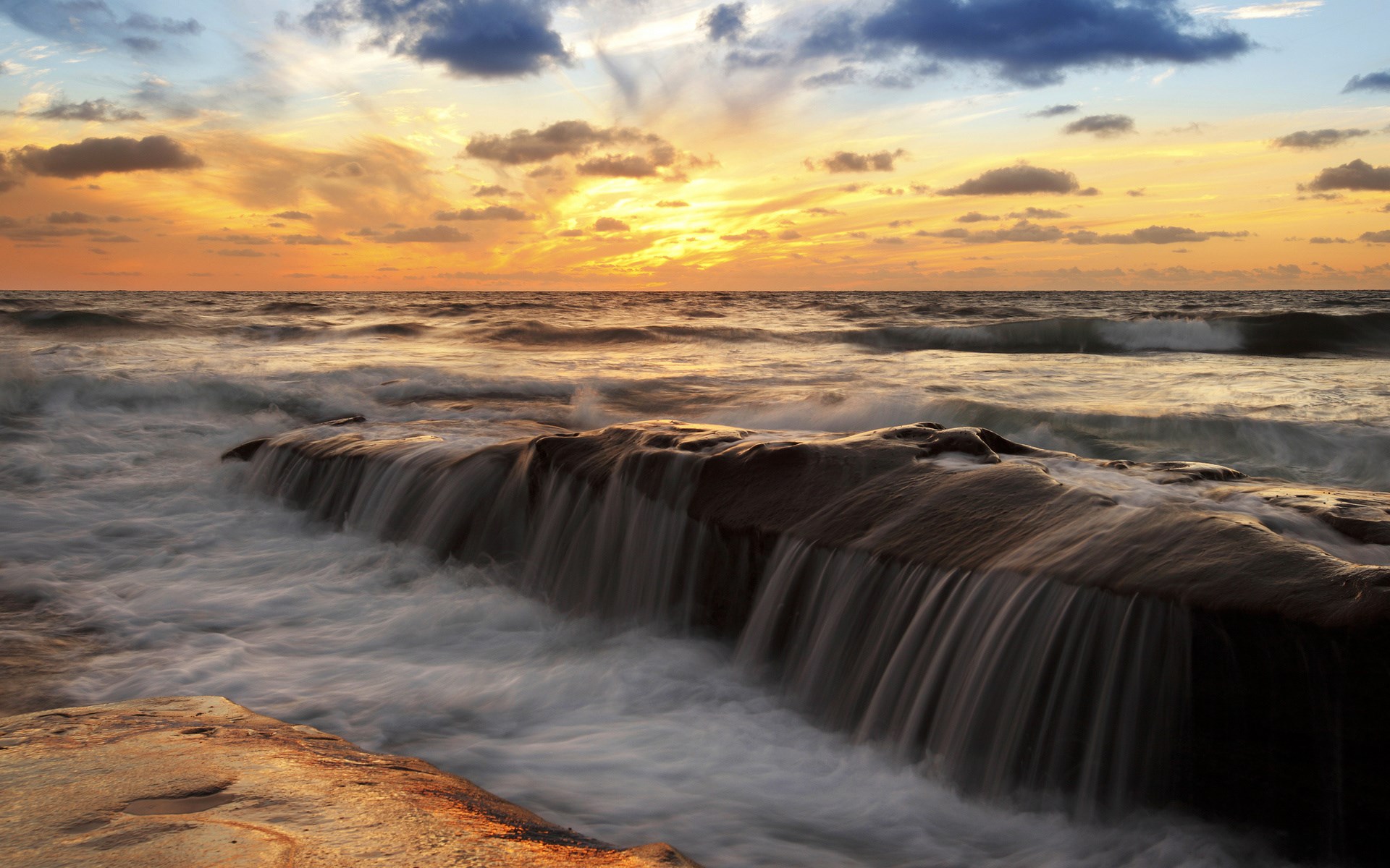 Ocean waves crashing over rocks at sunset HD Wallpaper