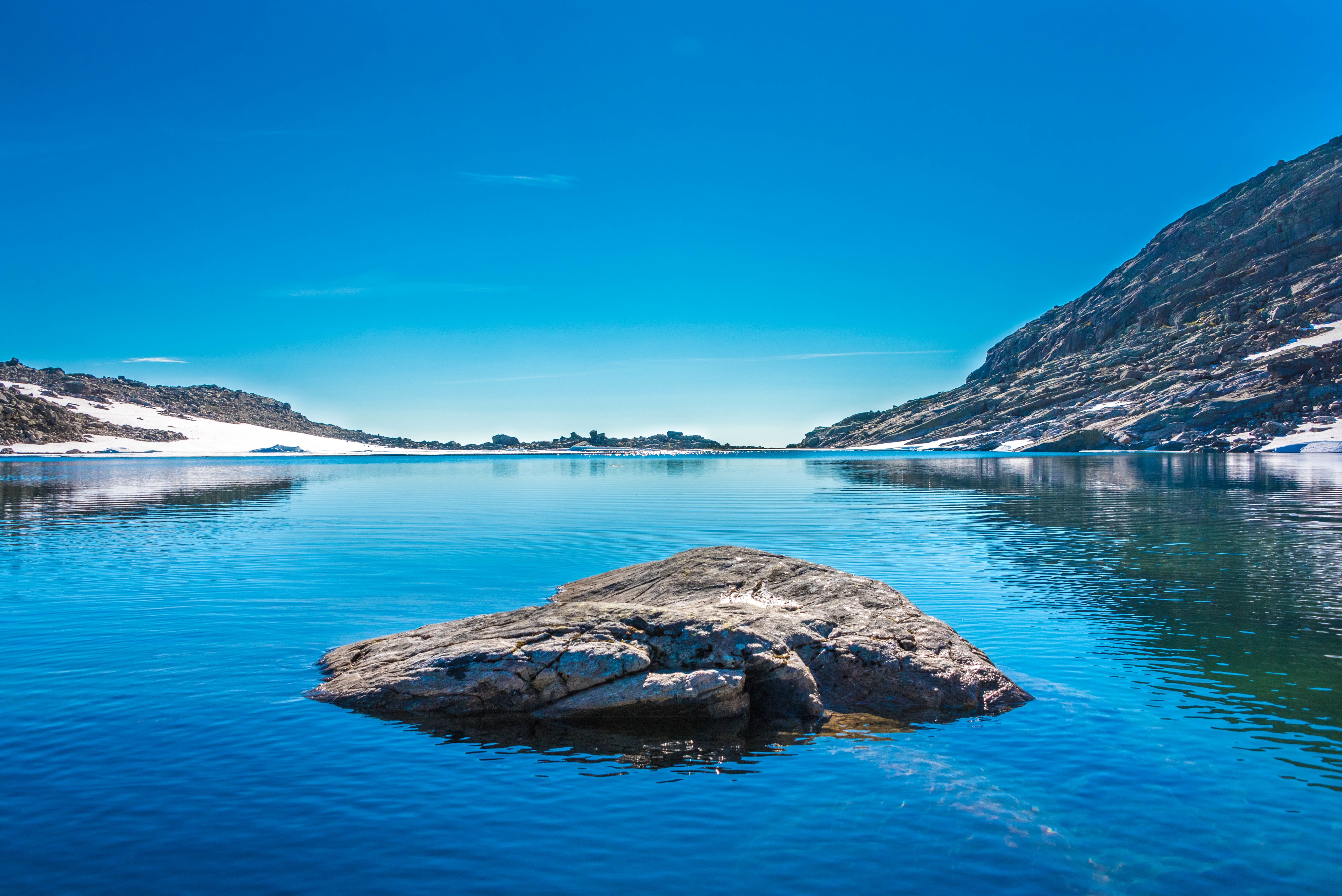 Rock in a mountain lake under a clear blue sky HD Wallpaper