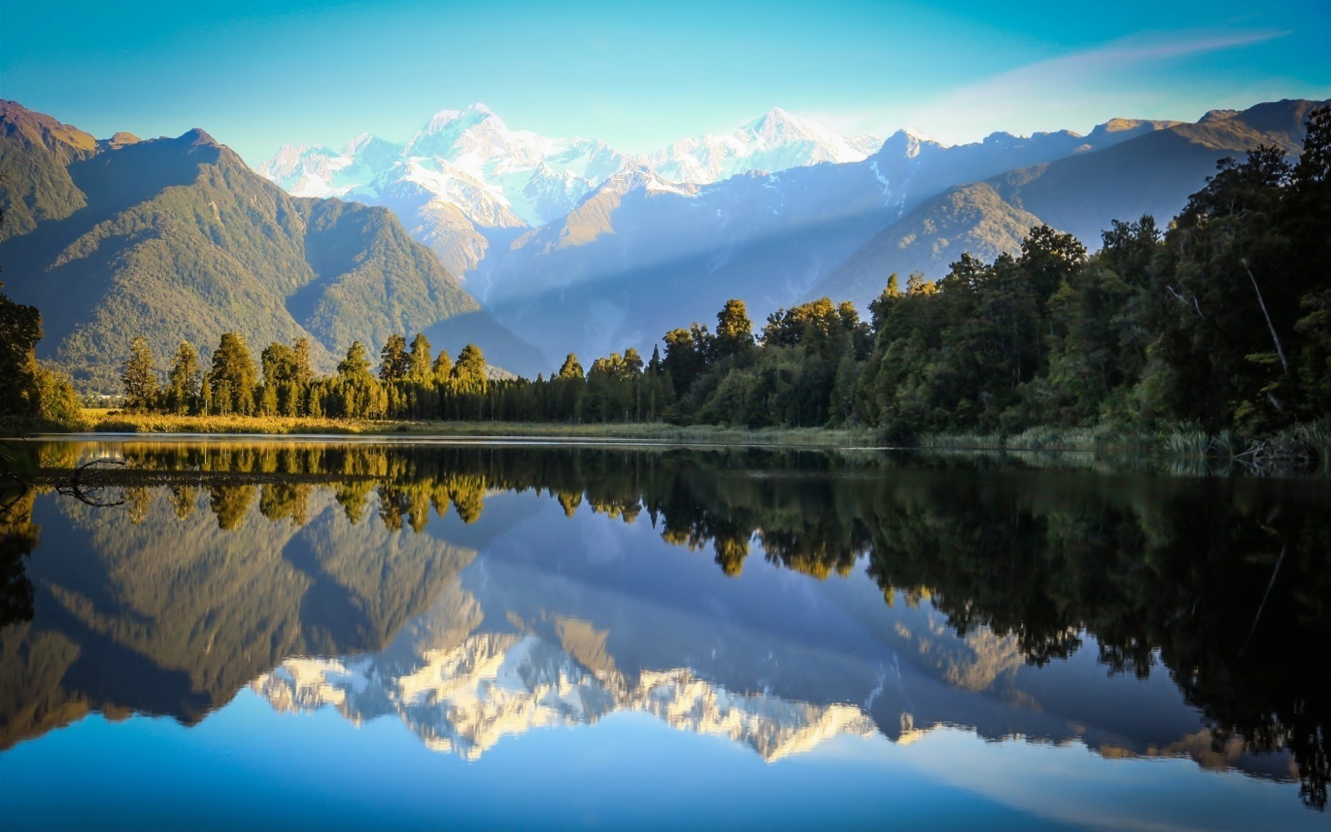 Snow-capped mountains reflected in a calm lake HD Wallpaper