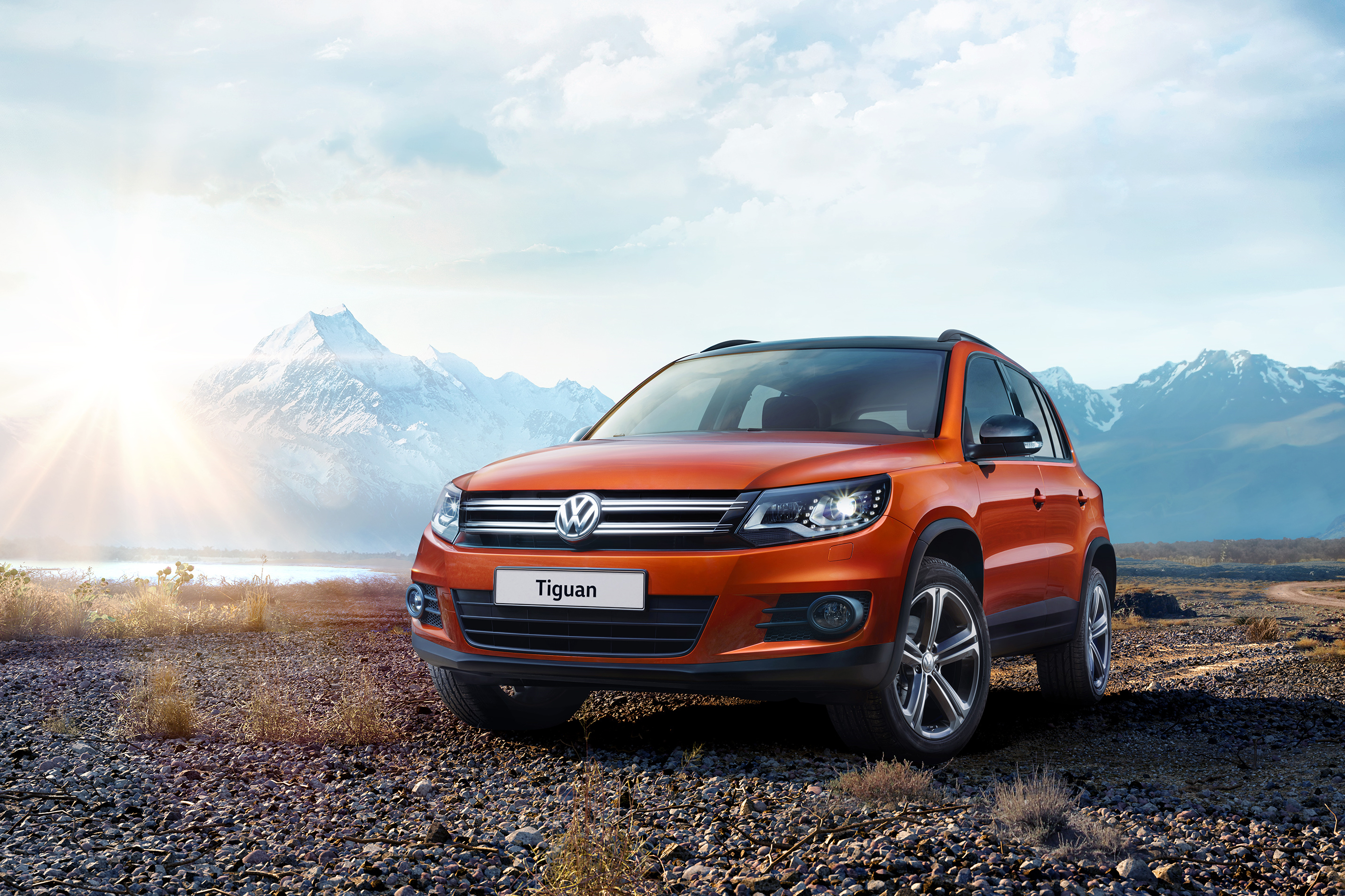 Orange Volkswagen Tiguan parked on rocky terrain with mountains HD Wallpaper