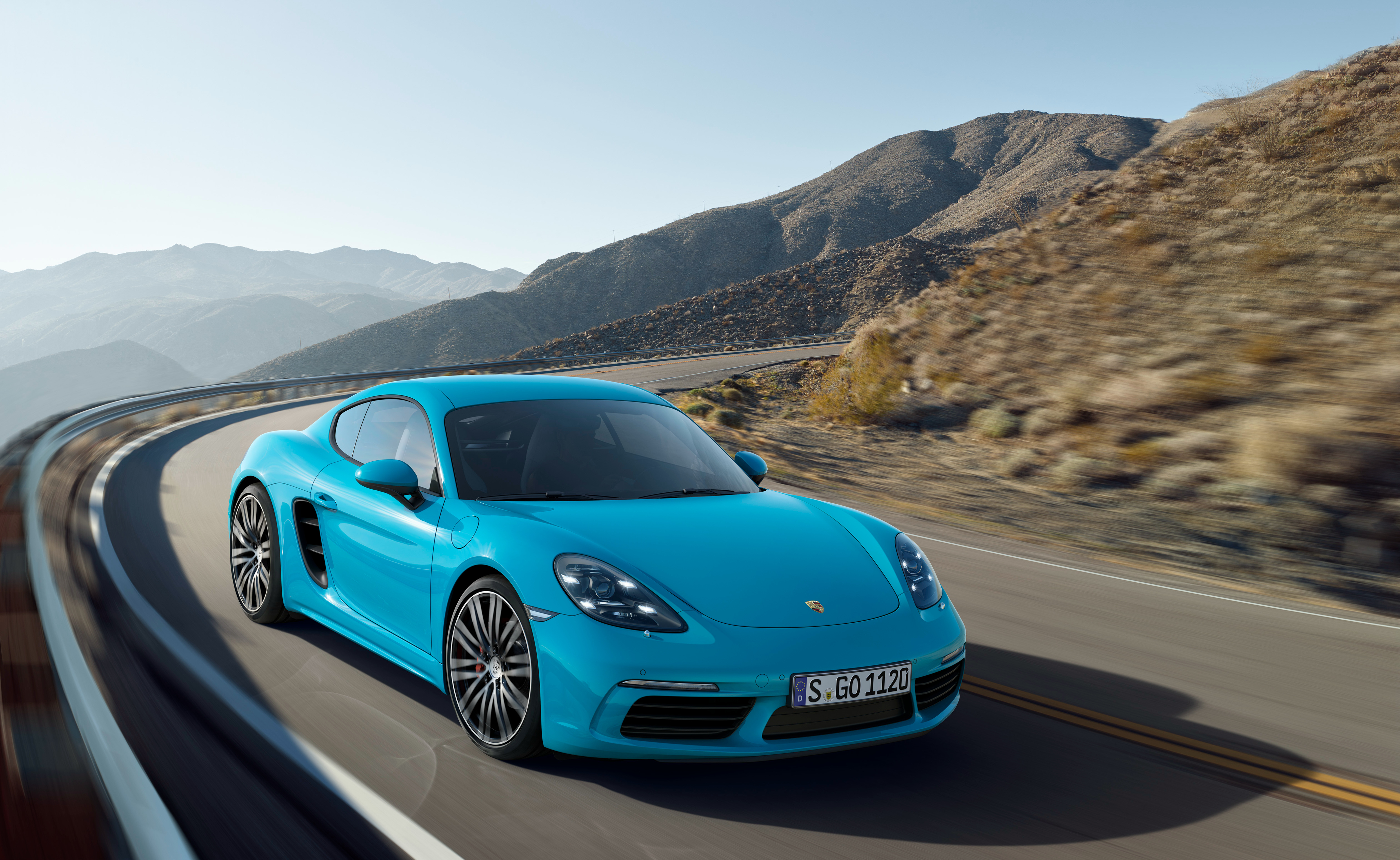 Blue Porsche 718 Cayman S driving on a mountain road HD Wallpaper