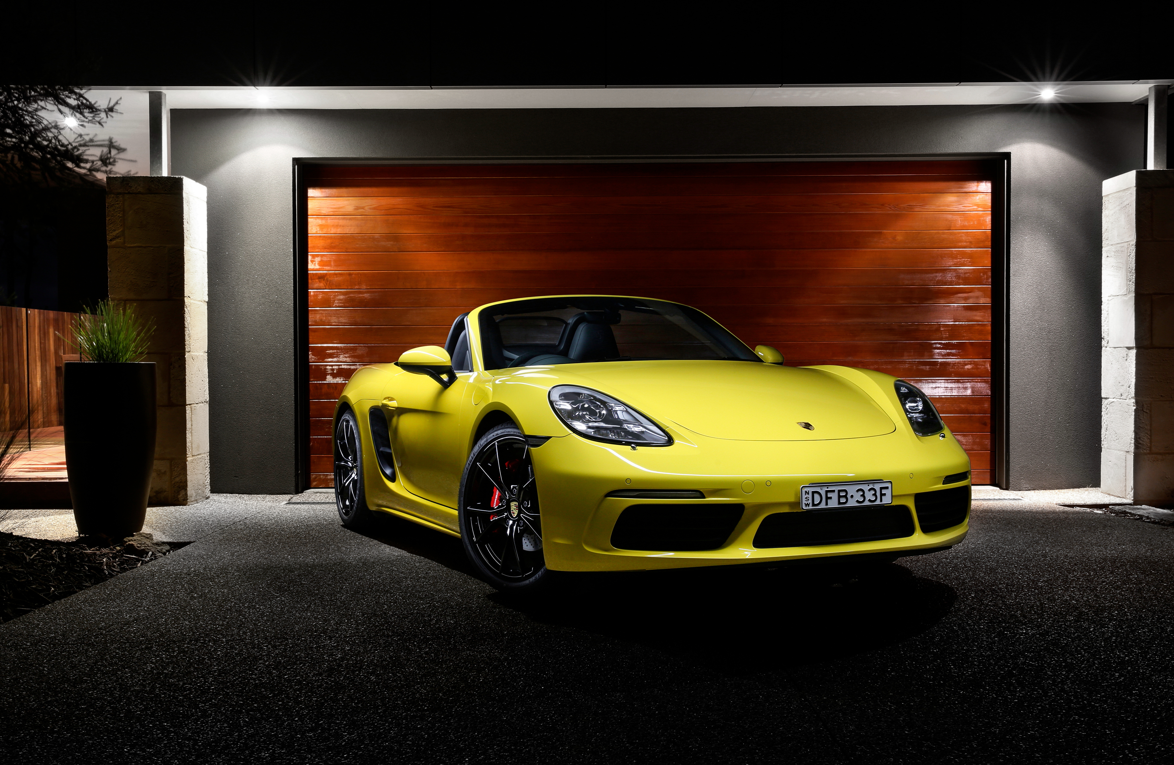 Yellow Porsche 718 Boxster parked in front of a garage HD Wallpaper