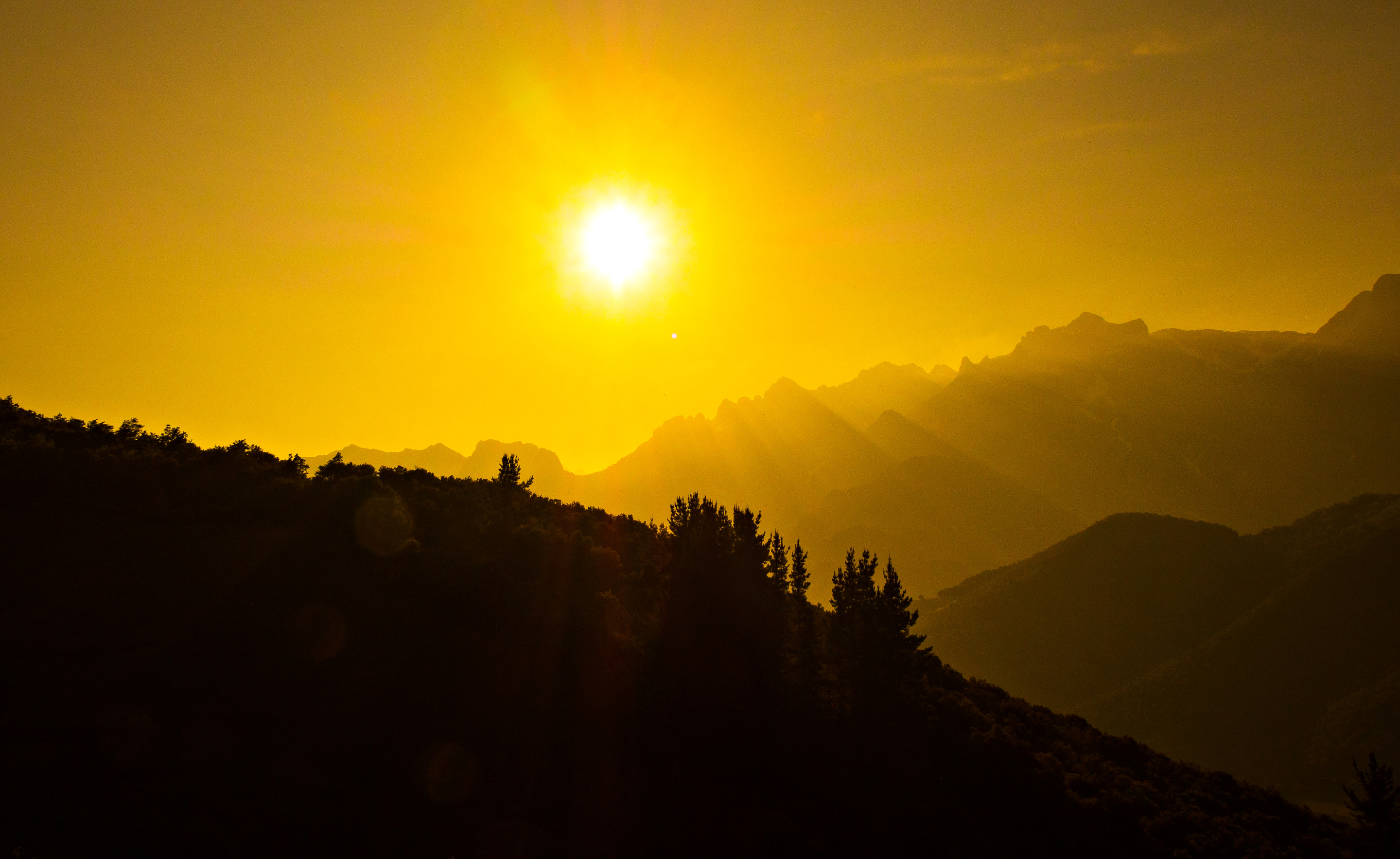 Sunrise over silhouetted mountains and trees HD Wallpaper