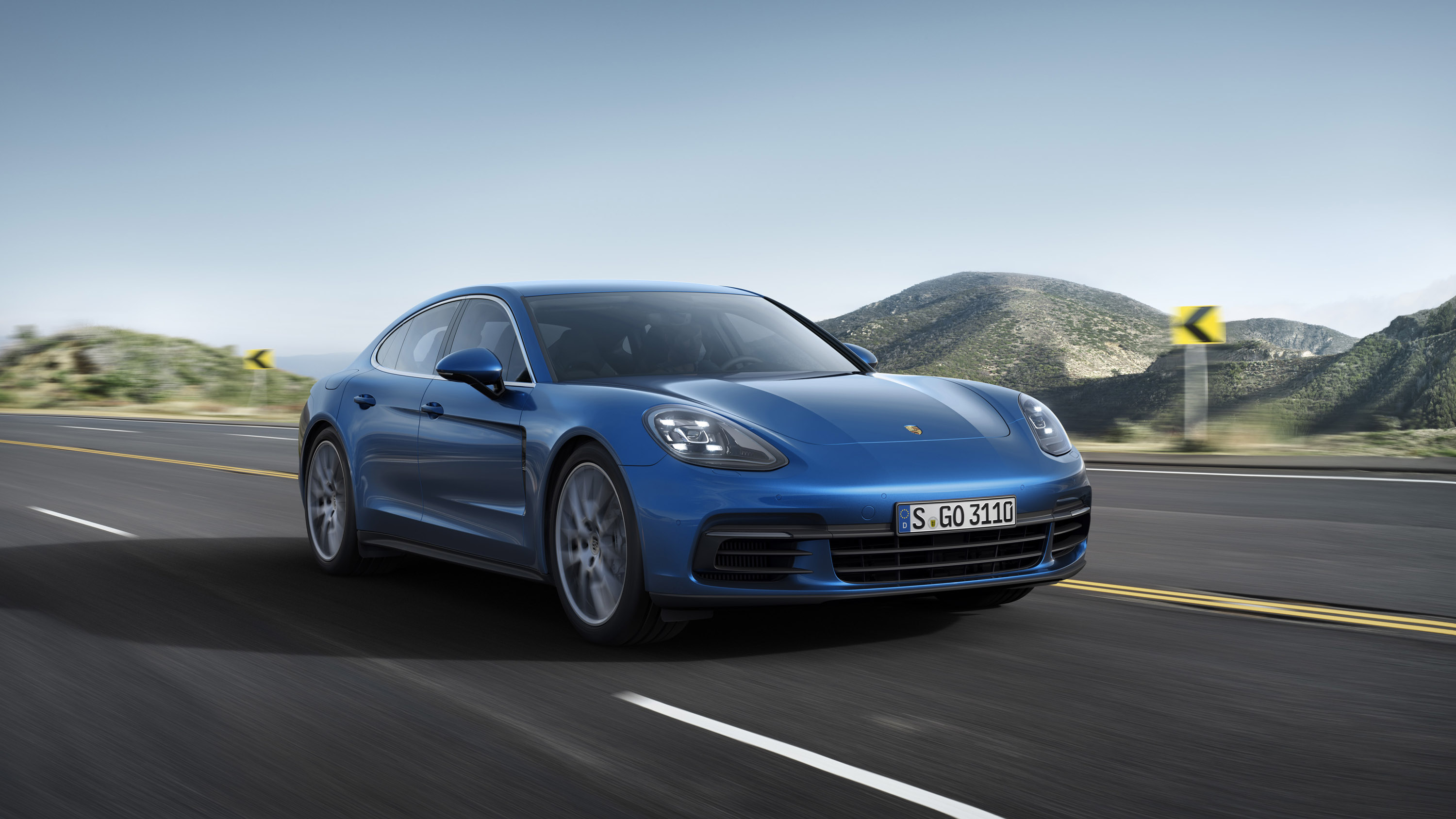 Blue Porsche Panamera driving on a scenic road HD Wallpaper
