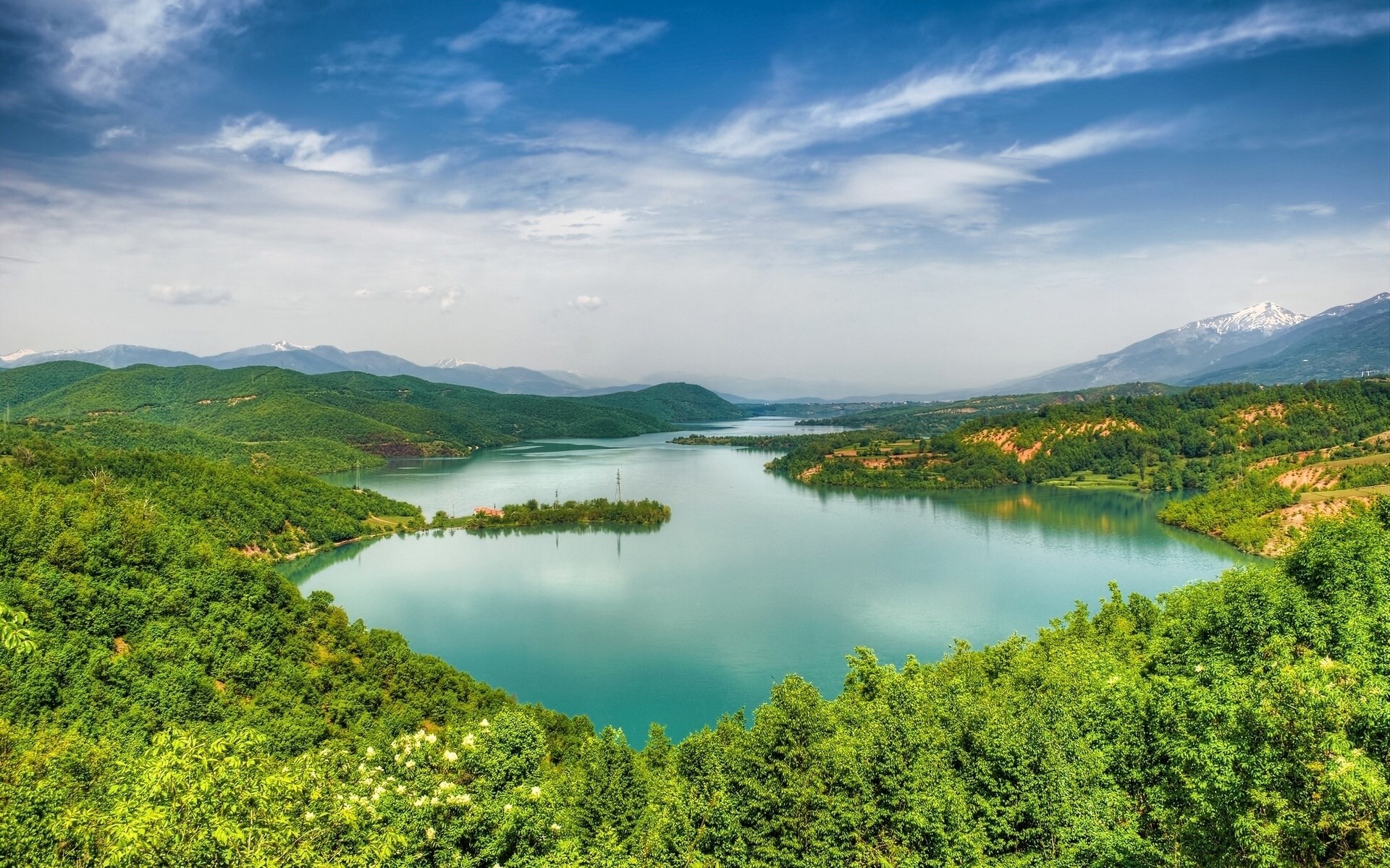 Vast lake surrounded by green hills and mountains under a cloudy sky HD Wallpaper