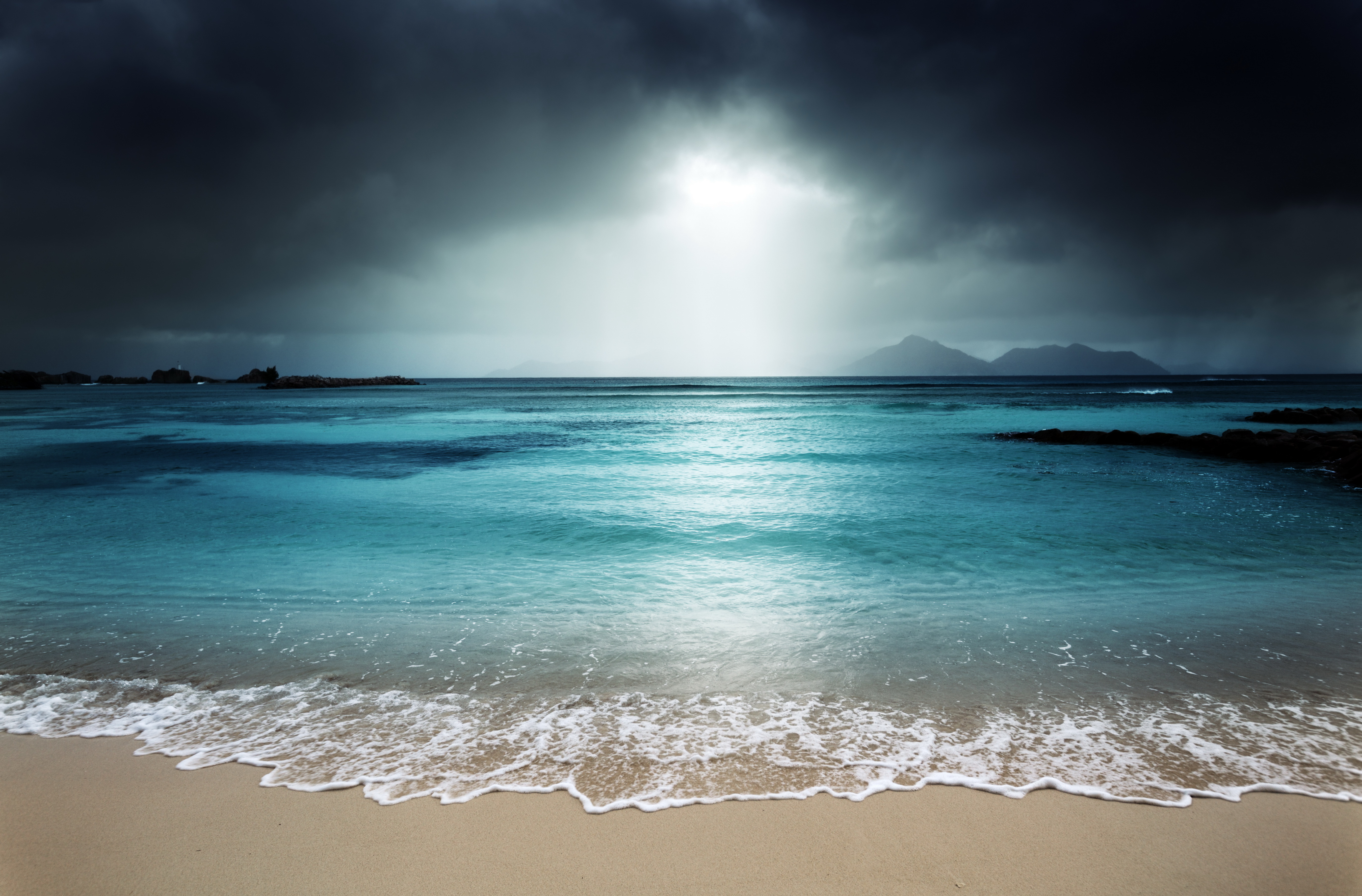 Beach with dark storm clouds and turquoise water HD Wallpaper