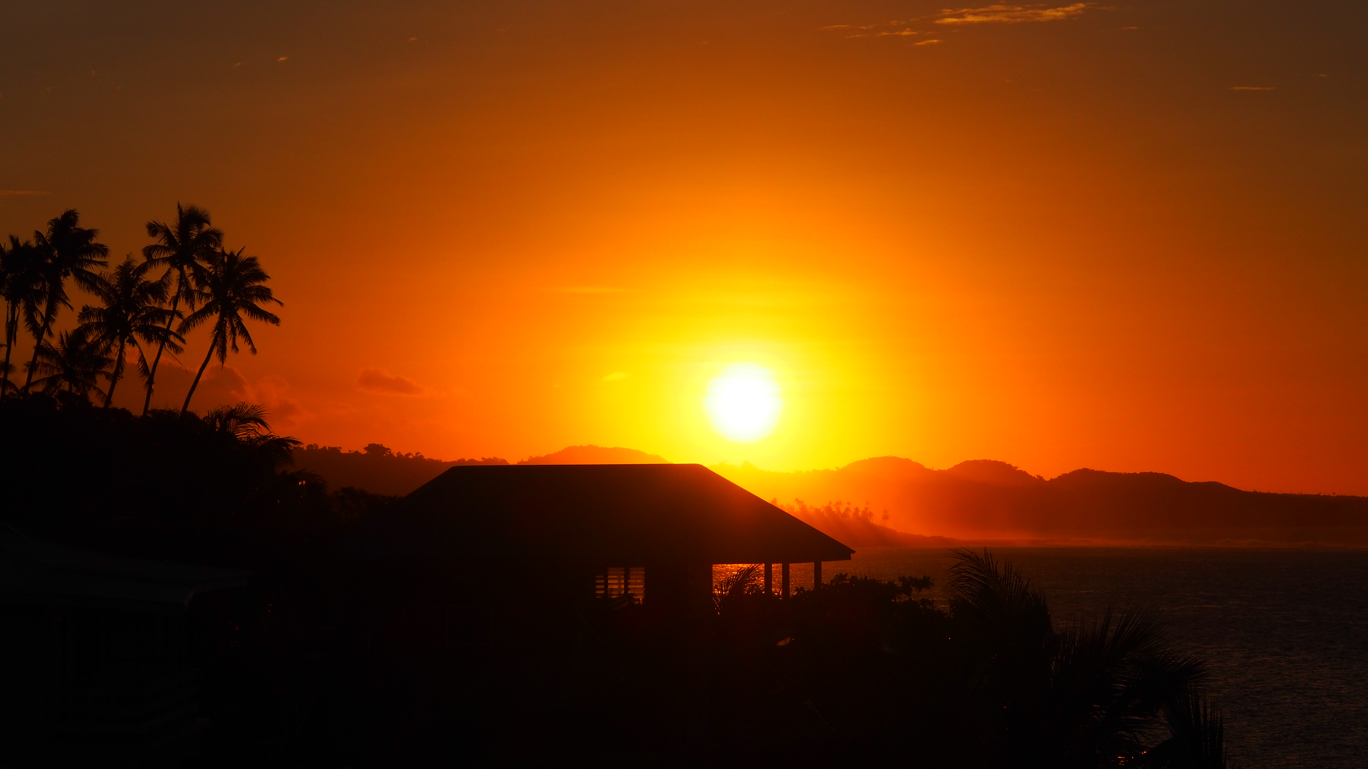 Sunset over the ocean with palm trees and a house HD Wallpaper
