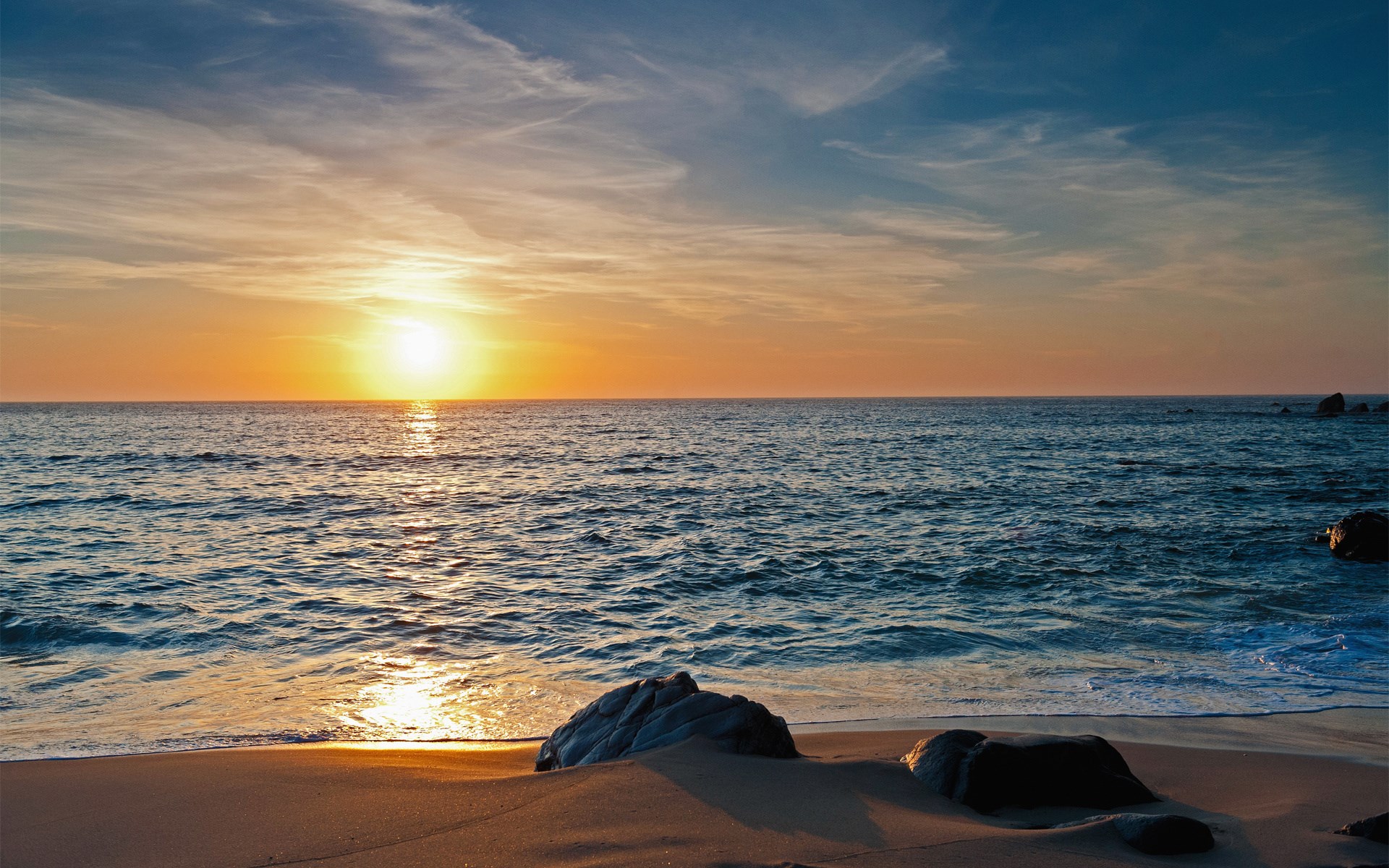 Sunset over the ocean with rocks on the beach HD Wallpaper
