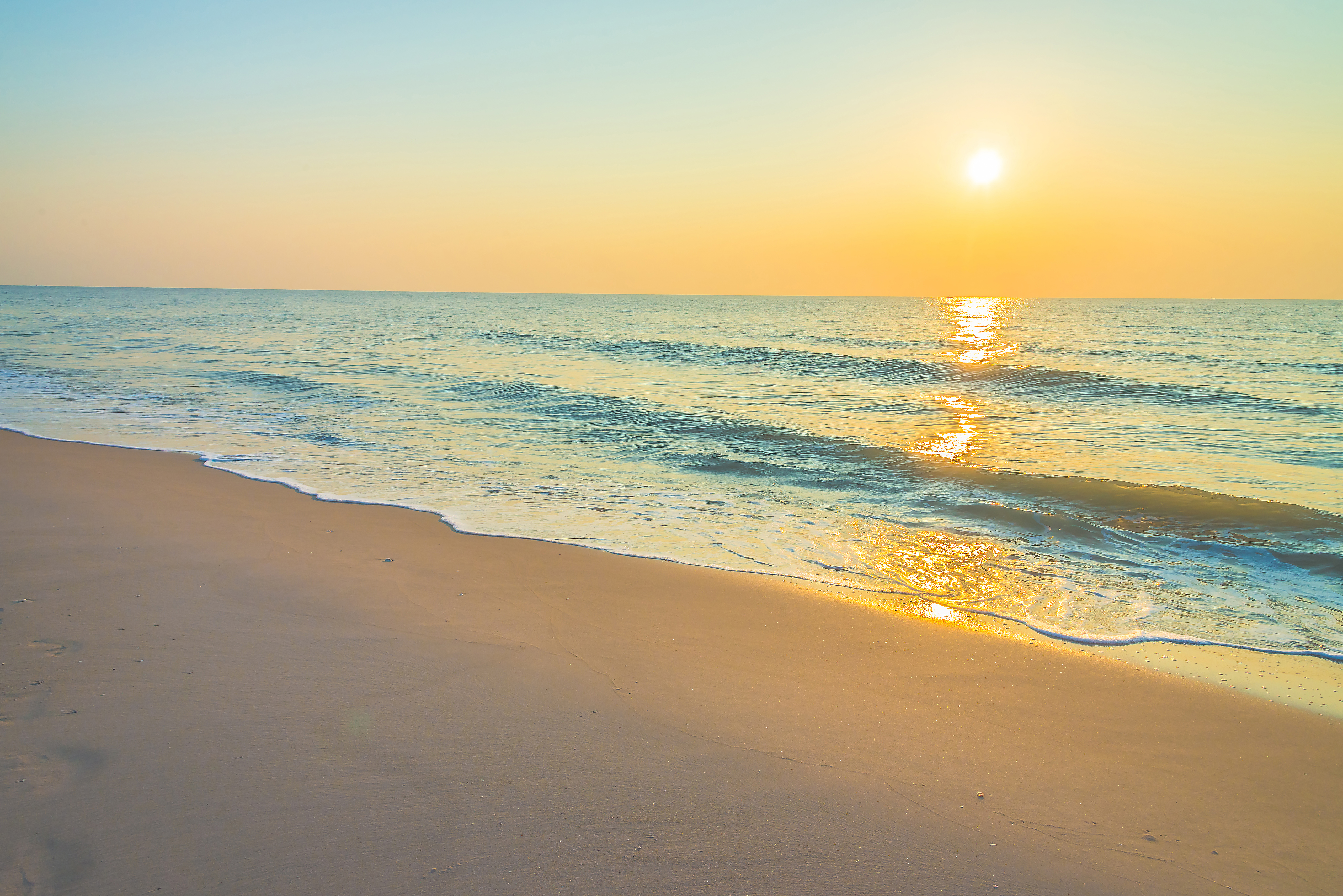 Sunset over the ocean waves on a sandy beach HD Wallpaper
