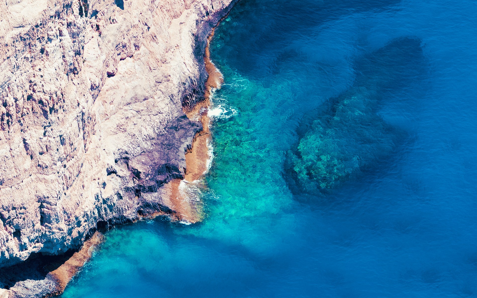 Aerial view of rocky coastline and clear blue sea HD Wallpaper