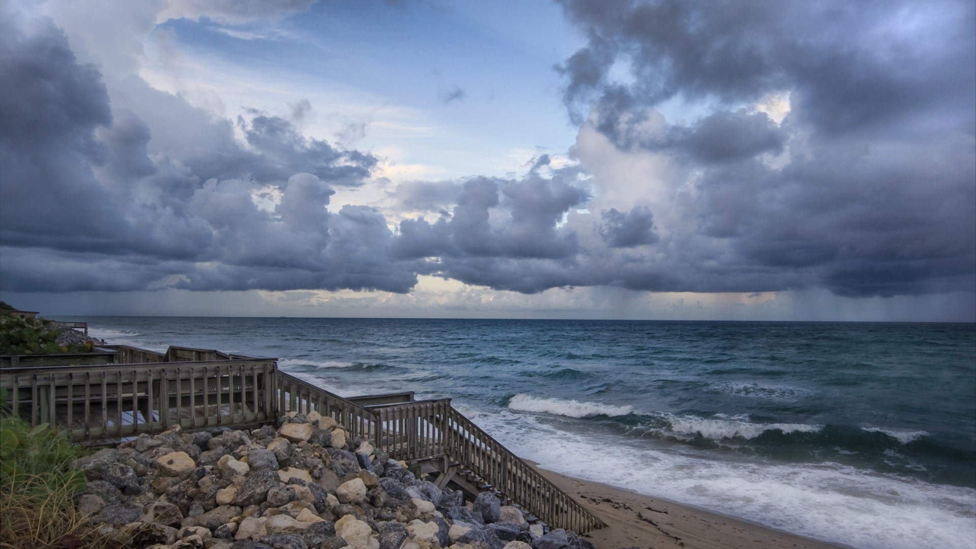 Wooden boardwalk stairs leading to a stormy beach HD Wallpaper