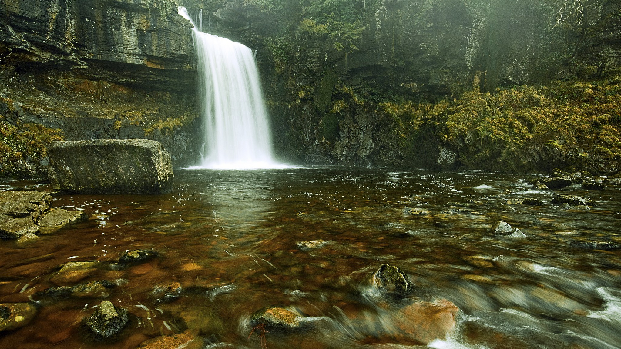 Waterfall cascading into a rocky river HD Wallpaper