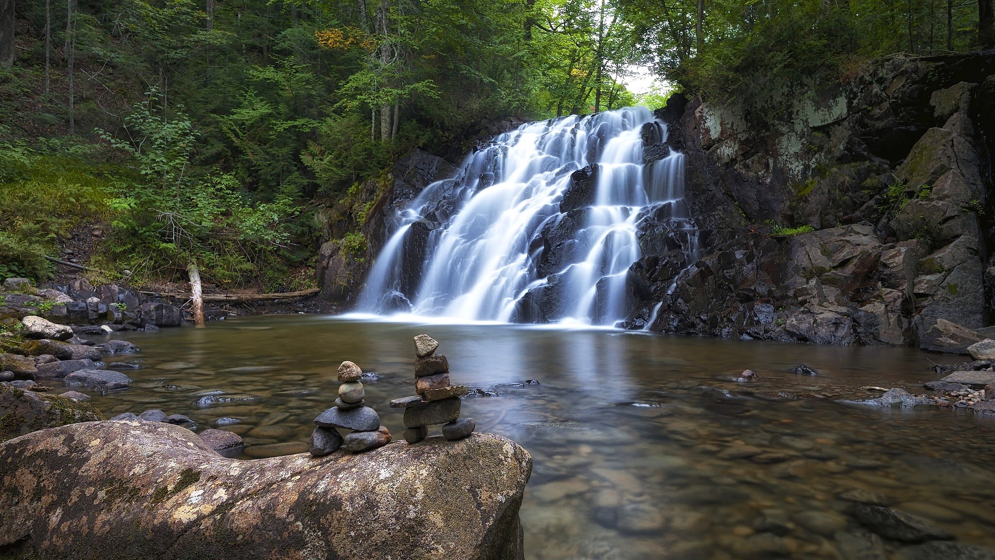 Waterfall cascading over rocks in a forest HD Wallpaper