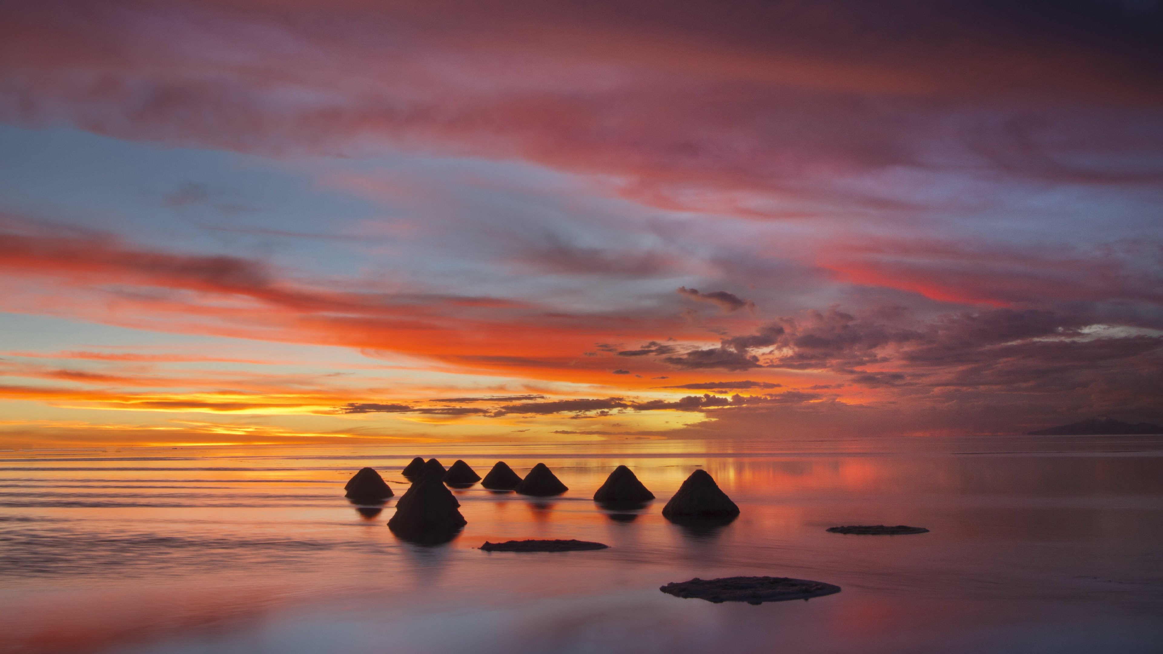 Conical rock formations in a calm sea at sunset HD Wallpaper