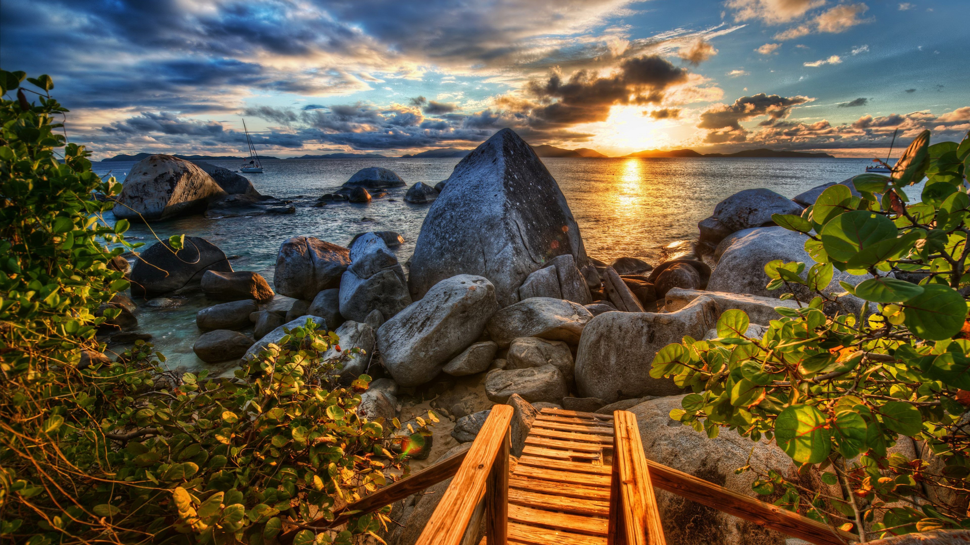 Wooden walkway to boulders and ocean at sunset HD Wallpaper
