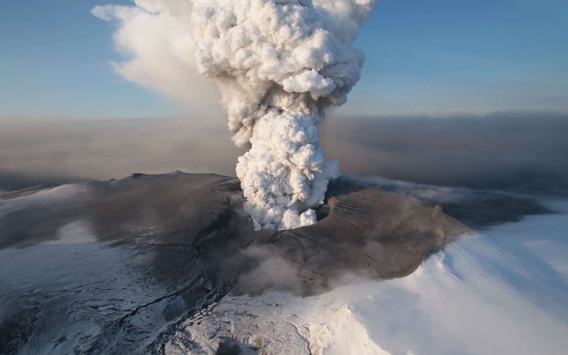 Volcano erupting ash cloud over snowy landscape HD Wallpaper