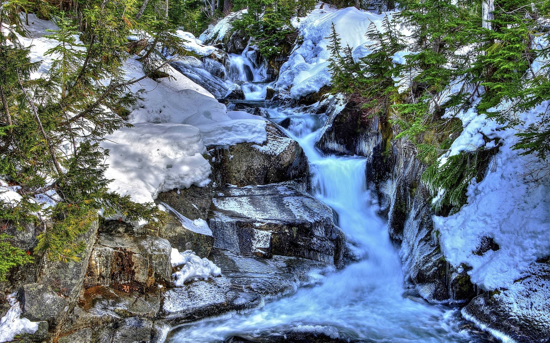 Winter waterfall flowing over rocks with snow and trees HD Wallpaper
