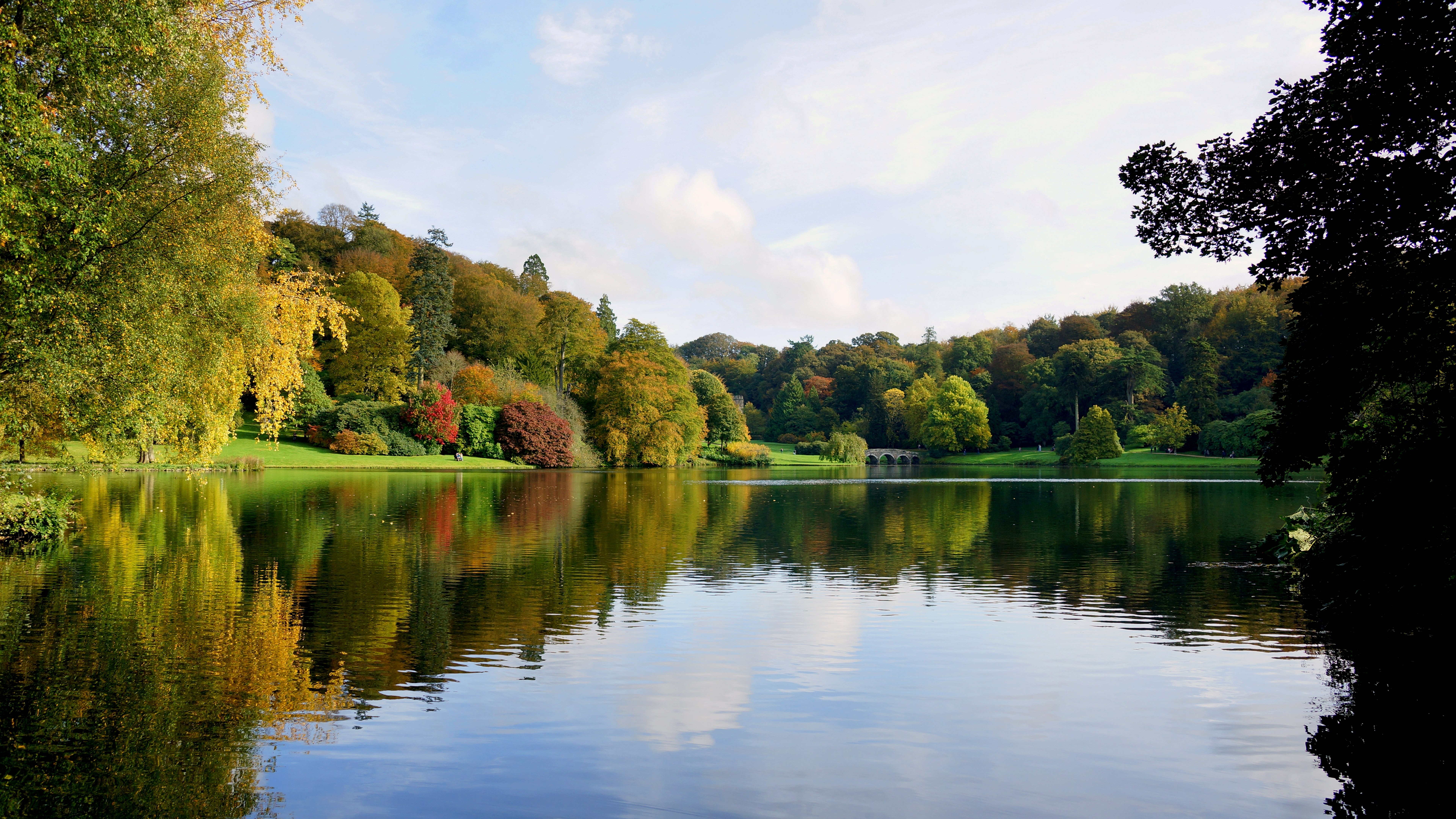 Autumn trees reflected in a lake with a bridge HD Wallpaper