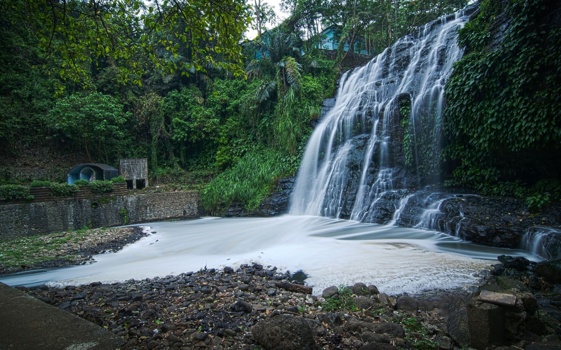 Waterfall cascading into a pool with rocky shore HD Wallpaper