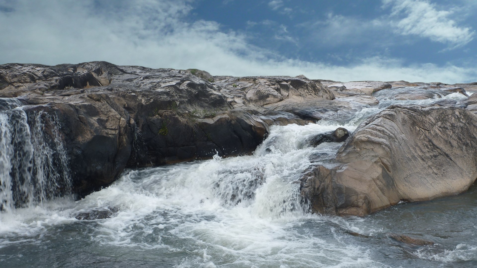 Rocky river with cascading water and blue sky HD Wallpaper