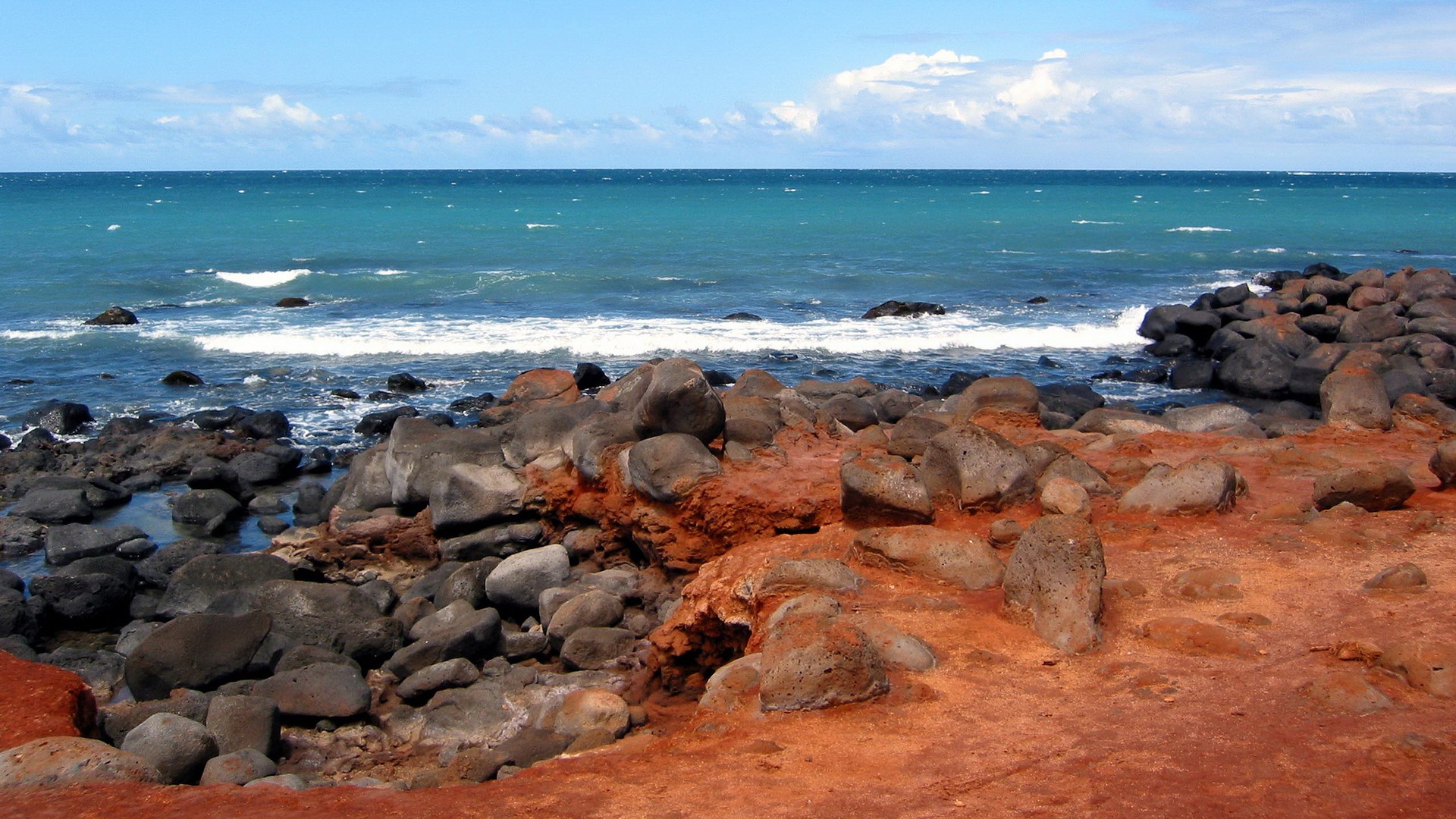 Rocky coastline with turquoise ocean and blue sky HD Wallpaper