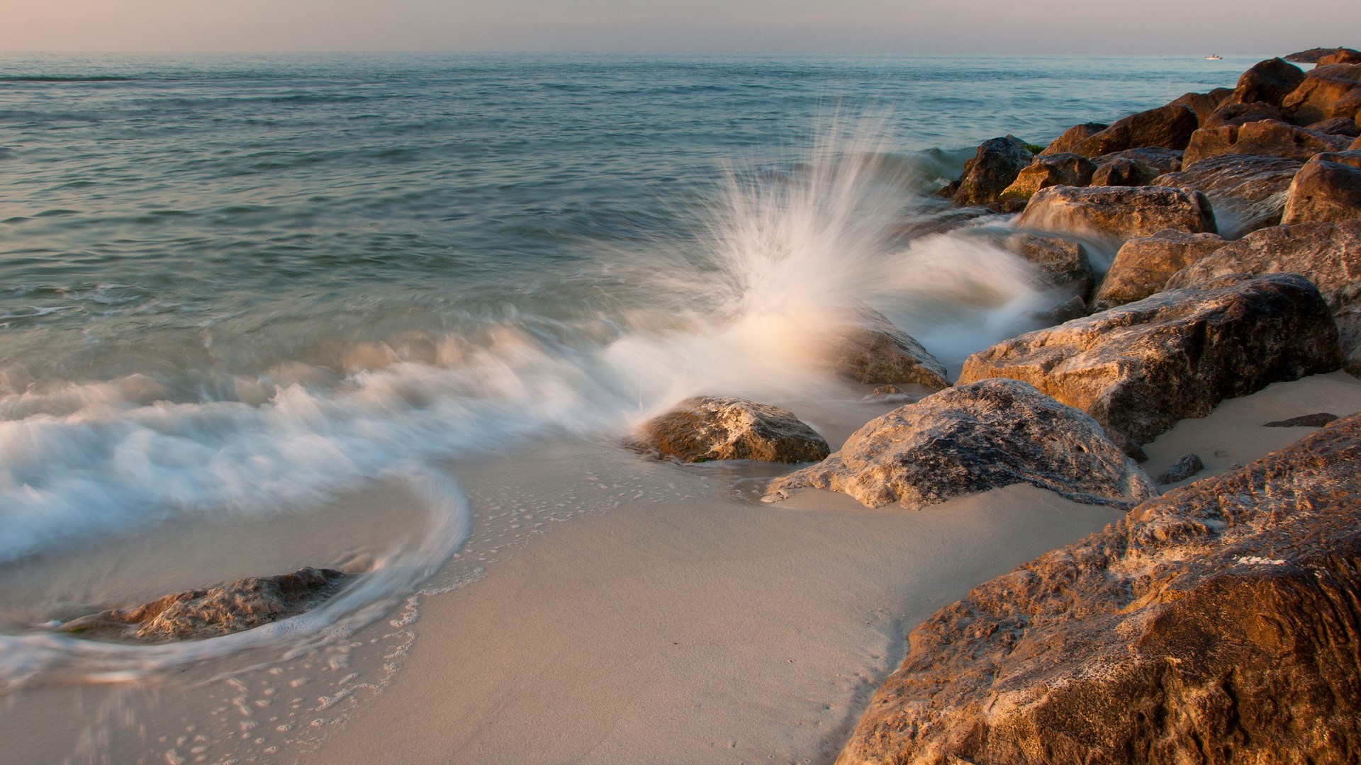Waves crashing on rocks at a beach HD Wallpaper