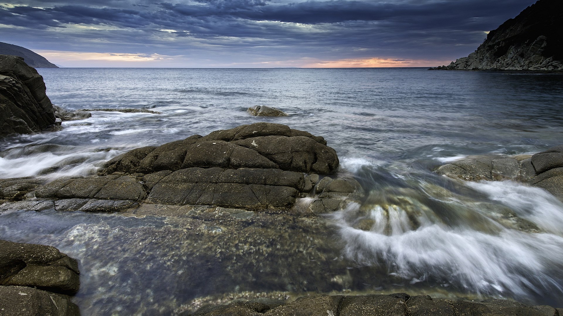 Ocean waves crashing on rocky shore at dusk HD Wallpaper