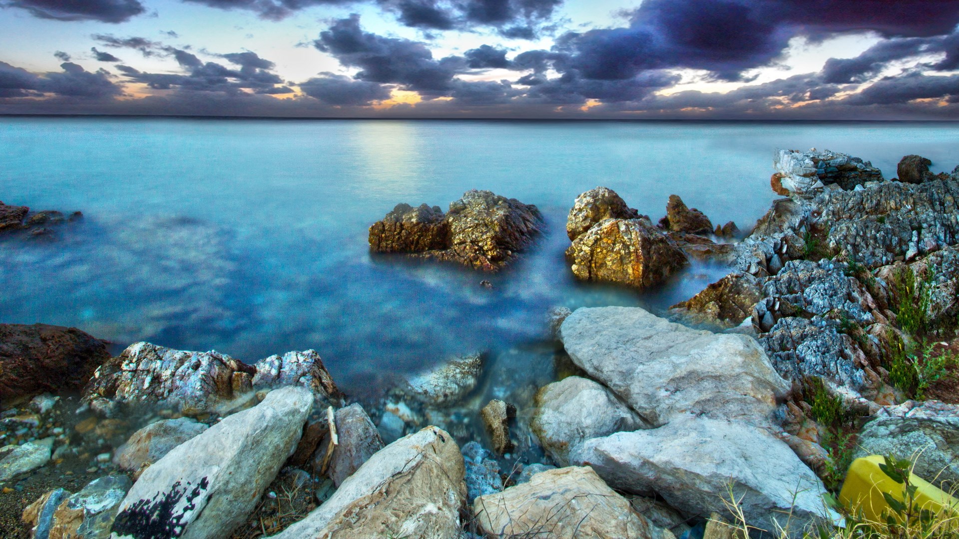 Rocky coastline with calm ocean and dramatic clouds HD Wallpaper