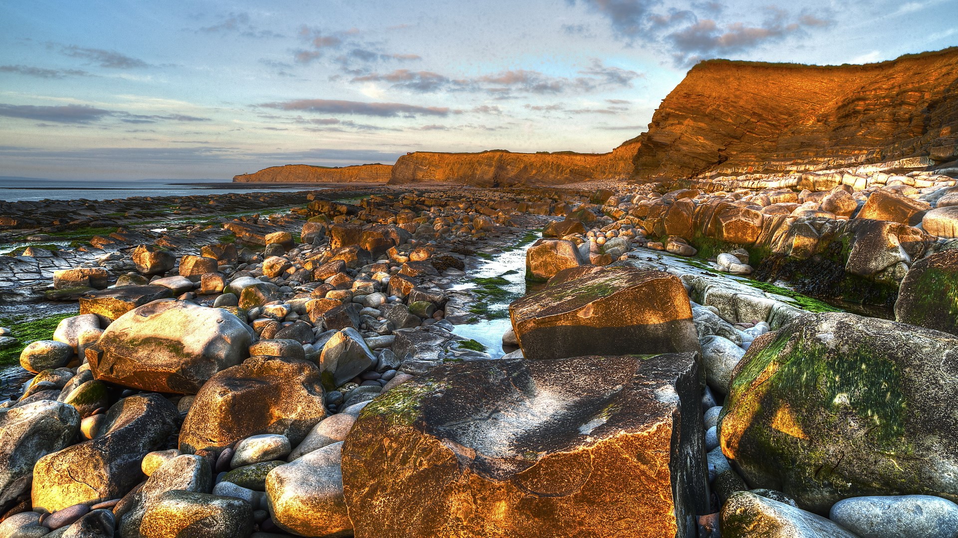Rocky coastline with cliffs and ocean at sunset HD Wallpaper