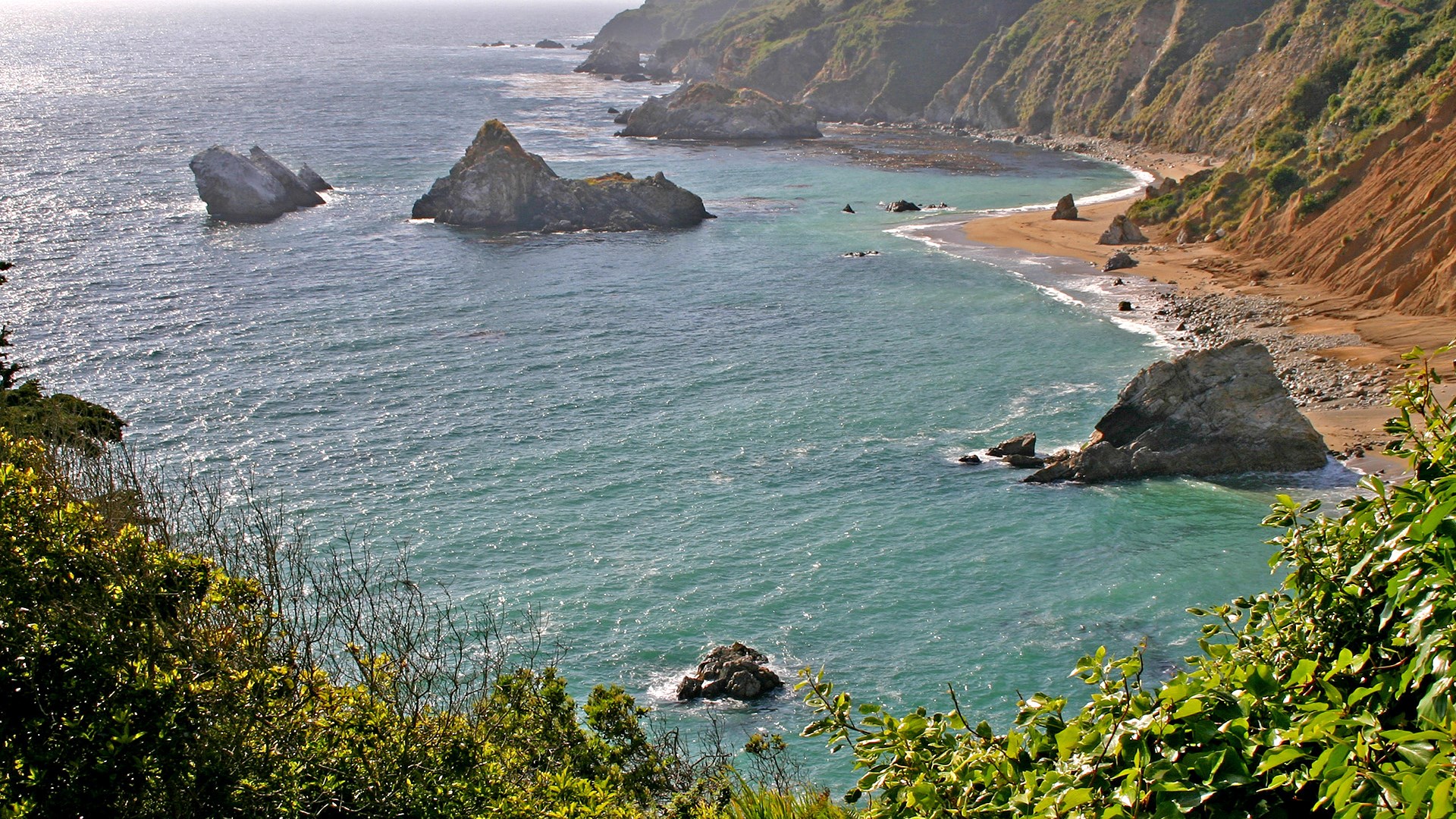 Rocky coastline with turquoise water and sandy beach HD Wallpaper