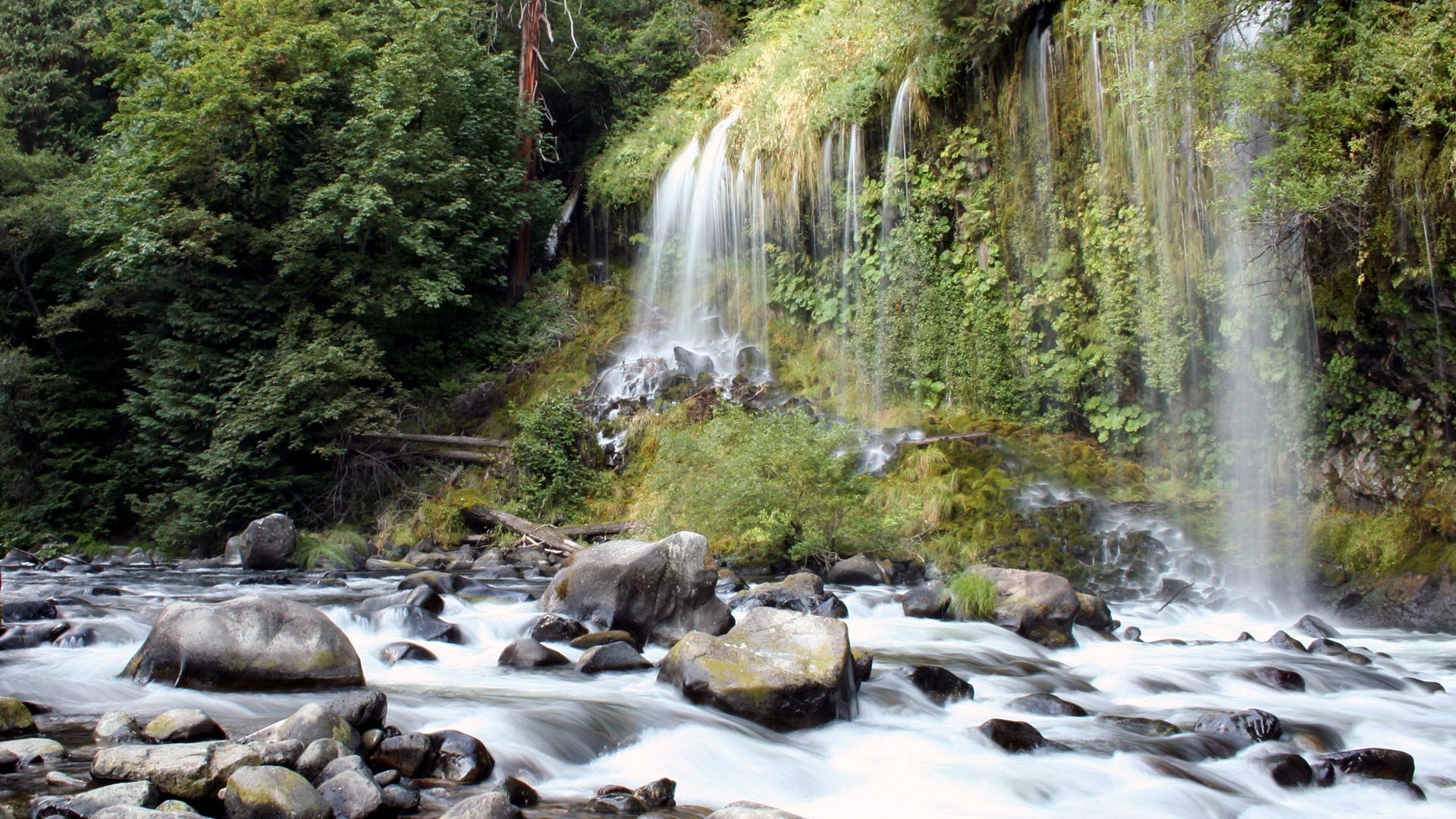 Waterfall cascading into a rocky river HD Wallpaper