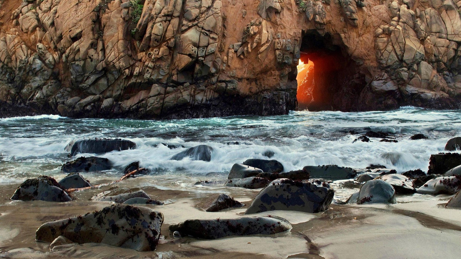 Ocean waves crashing against a rocky cave entrance HD Wallpaper