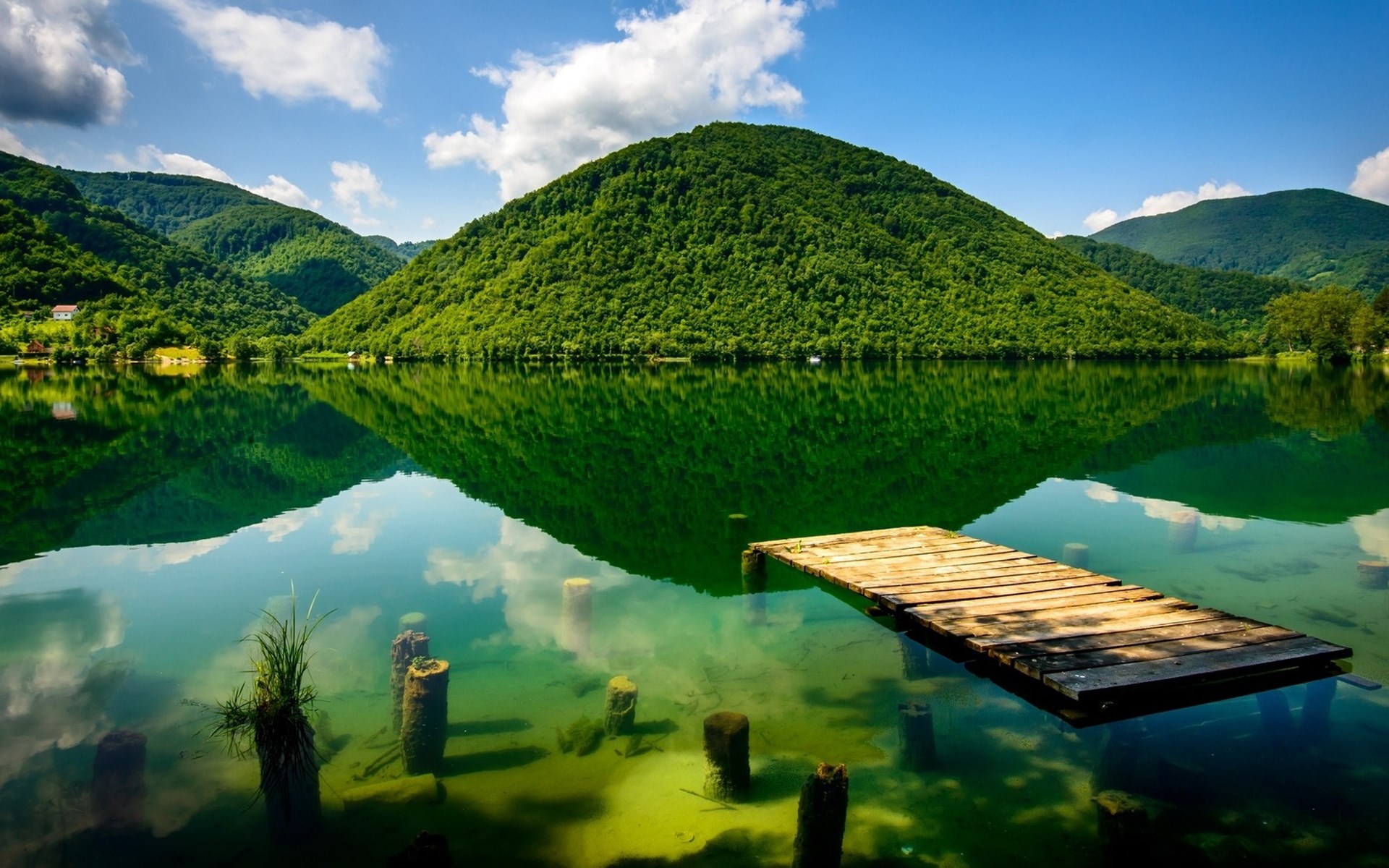 Wooden pier on a clear lake with green mountains HD Wallpaper