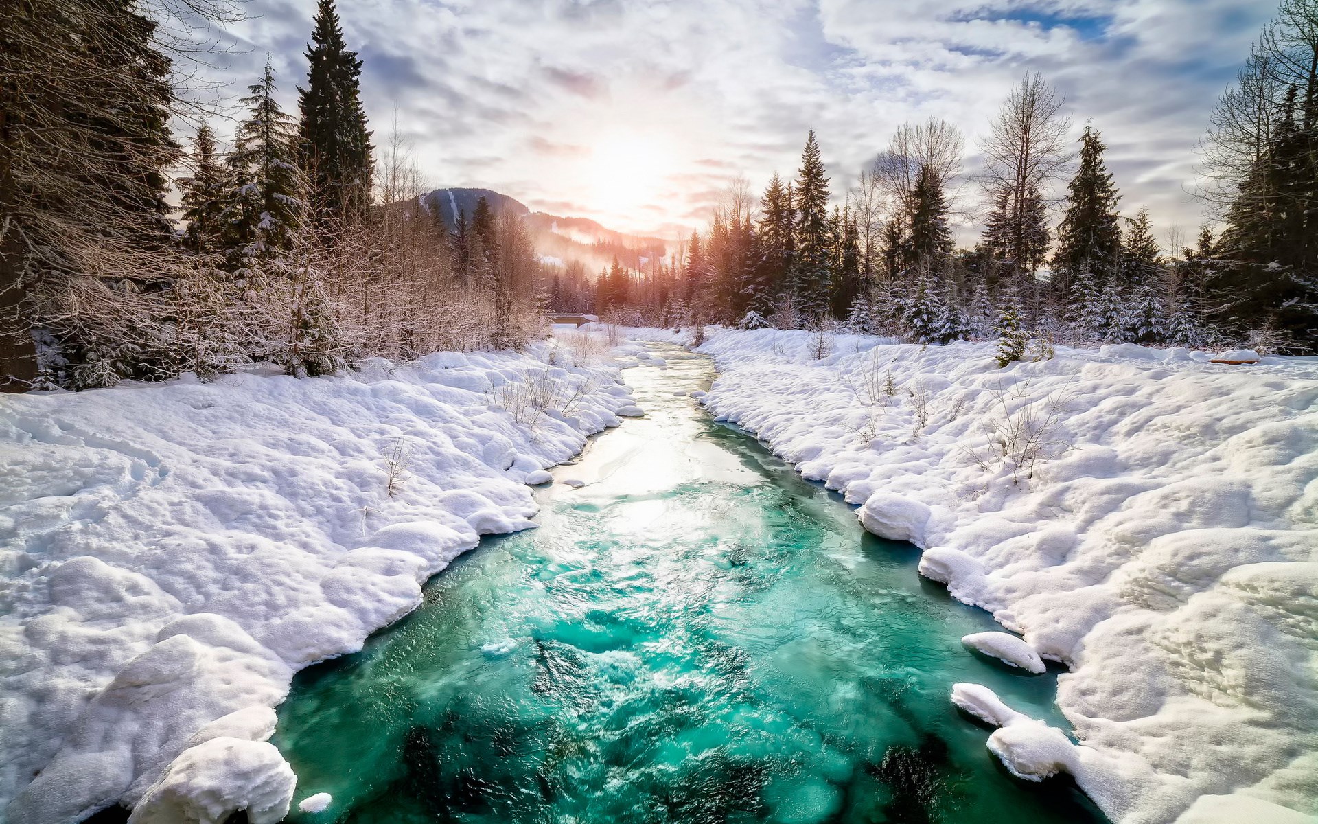Turquoise river flowing through a snowy forest at sunset HD Wallpaper