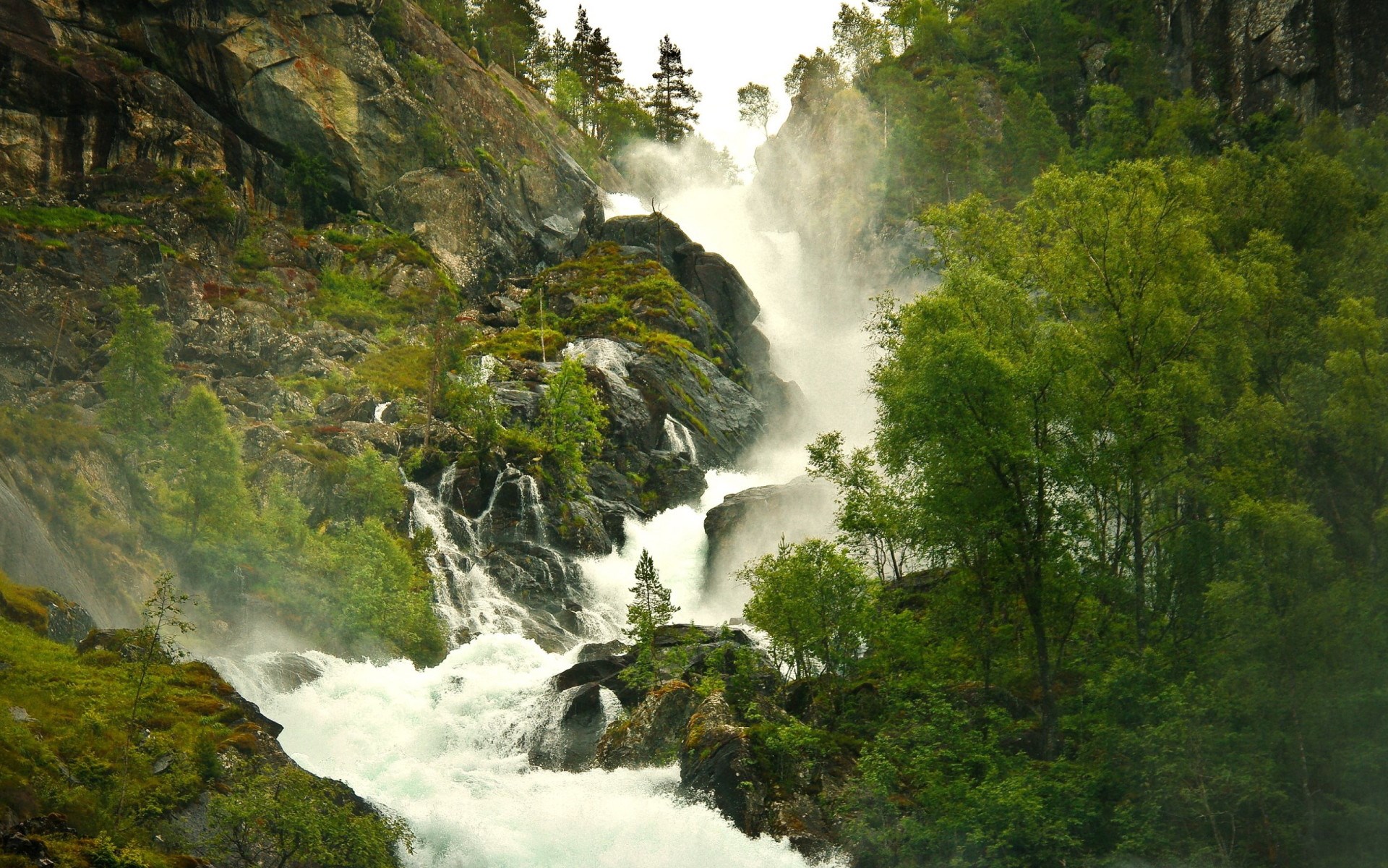 Waterfall cascading down a rocky, forested mountainside HD Wallpaper