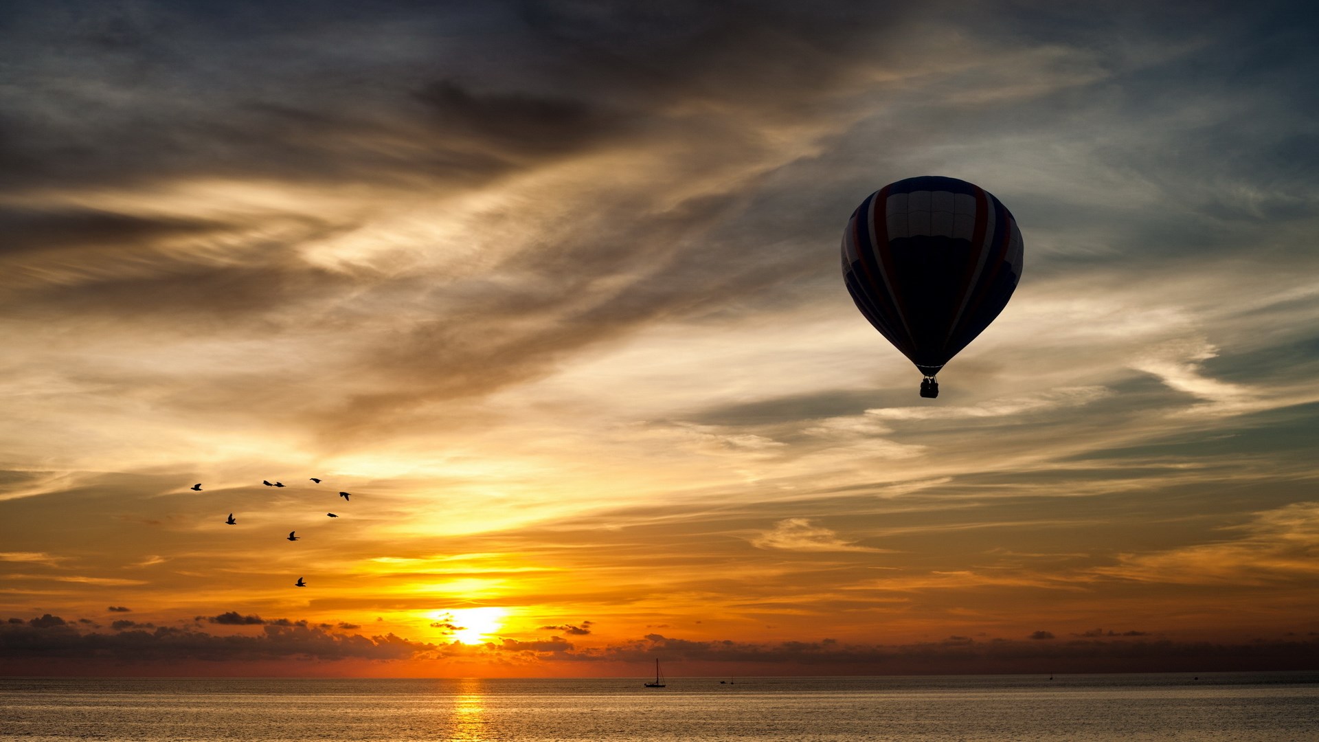 Hot air balloon over the ocean at sunset with birds HD Wallpaper