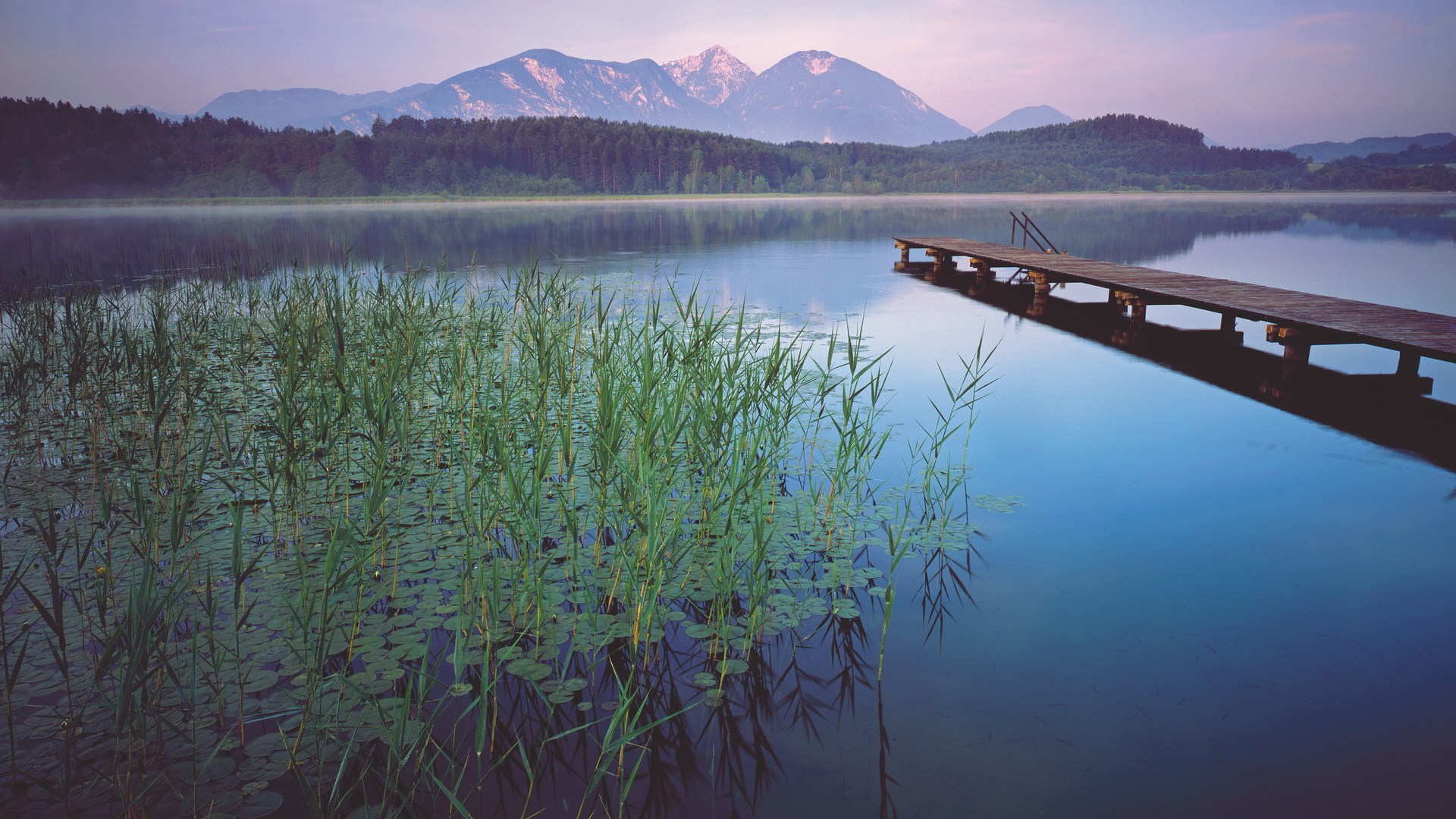 Wooden pier on a calm lake with mountains in the background HD Wallpaper