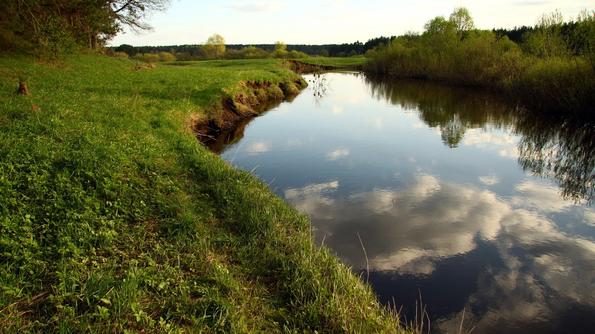 A winding river flows through a grassy landscape HD Wallpaper