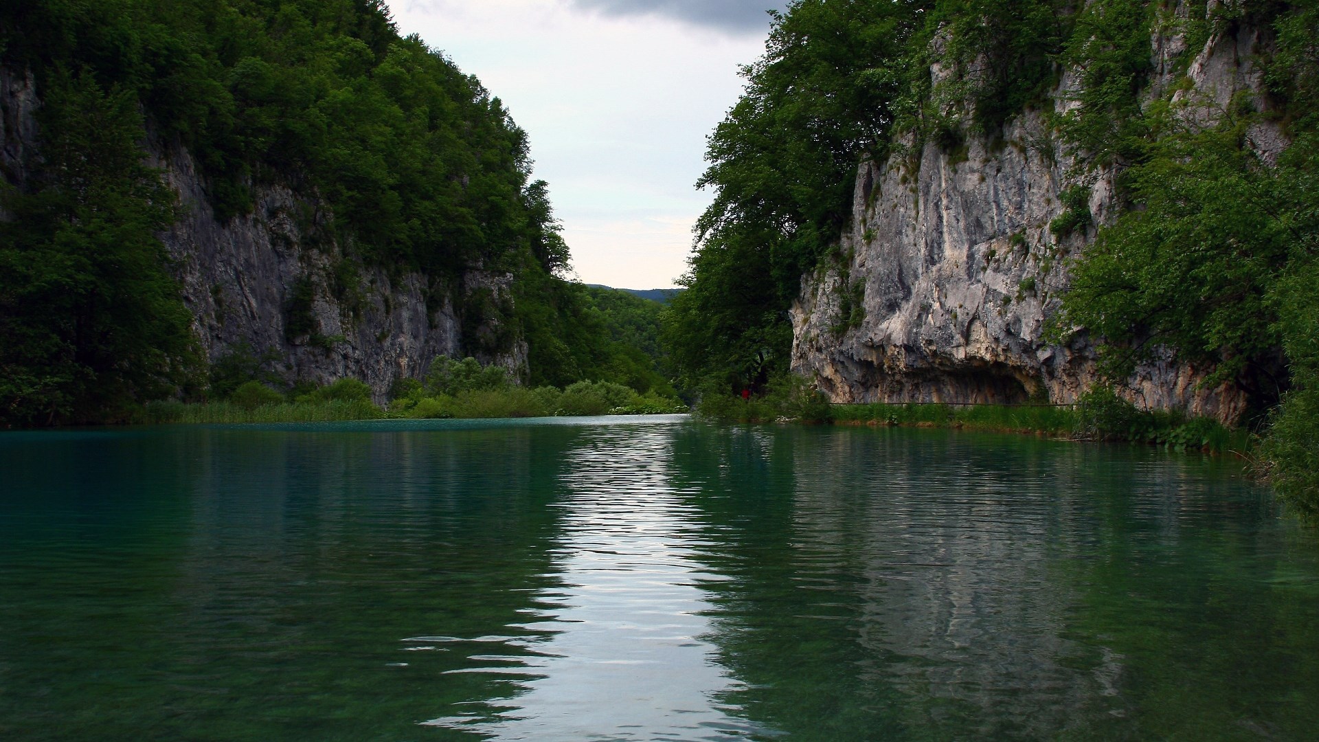 Turquoise lake between rocky cliffs and green forest HD Wallpaper
