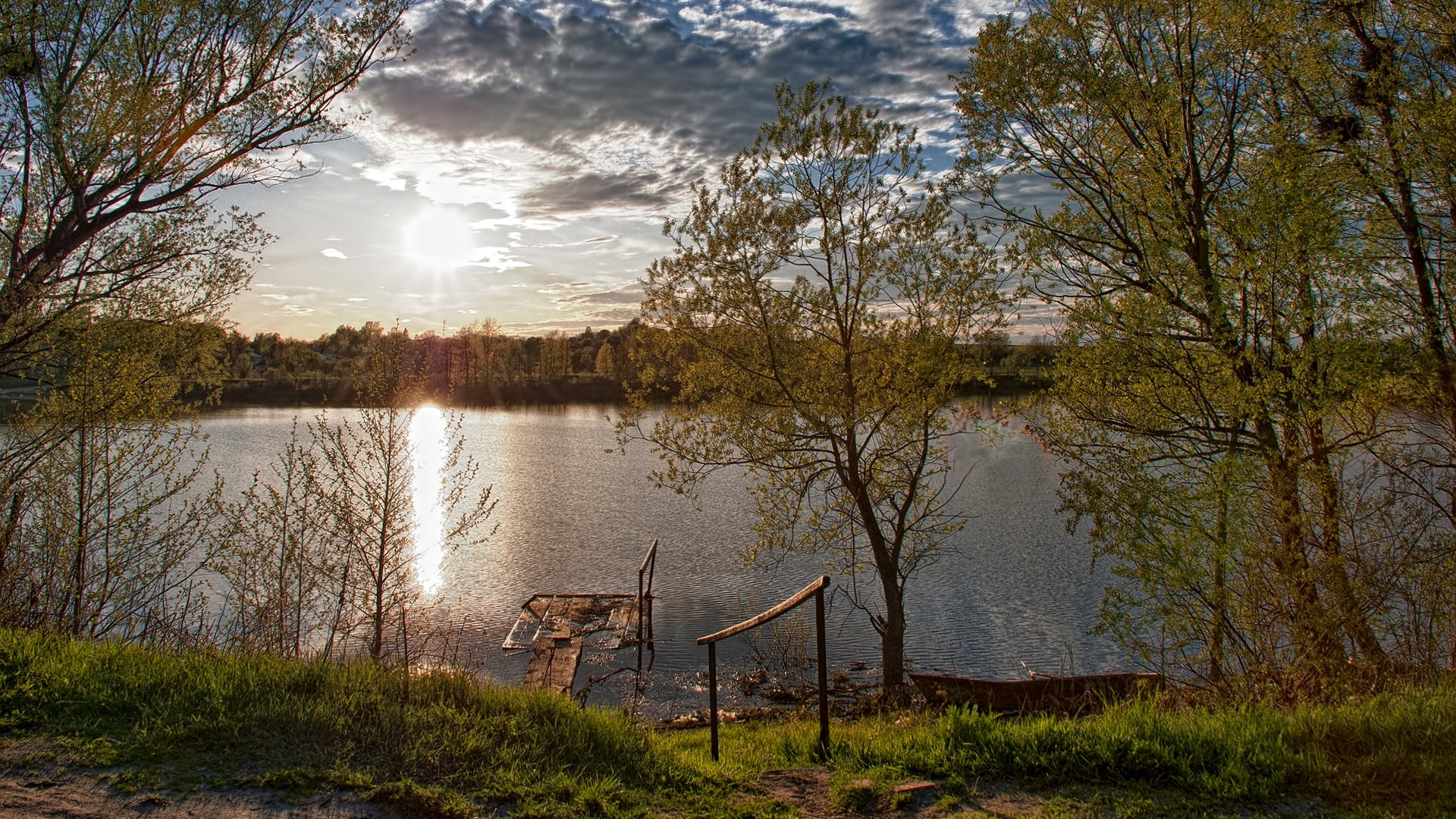 Sunset over a calm lake with trees and a small dock HD Wallpaper