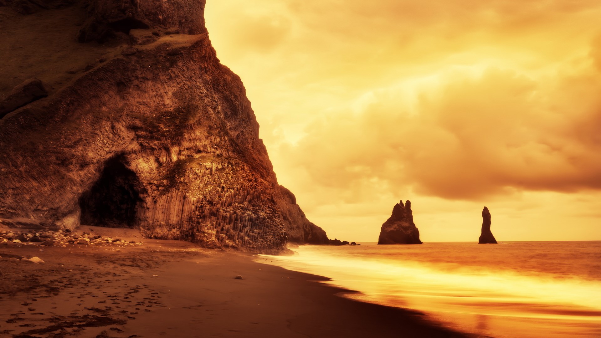 Cave entrance on a black sand beach with sea stacks HD Wallpaper