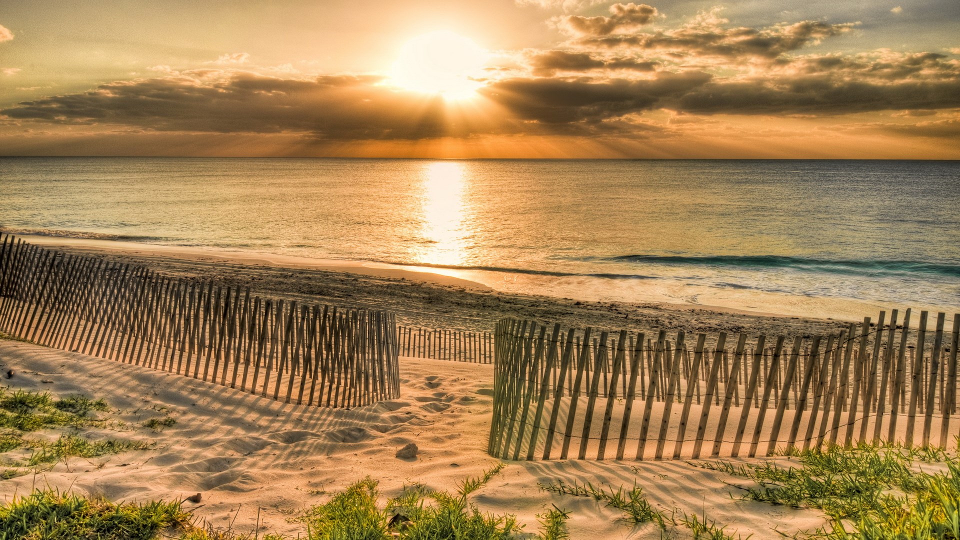 Beach fence at sunset with ocean waves HD Wallpaper