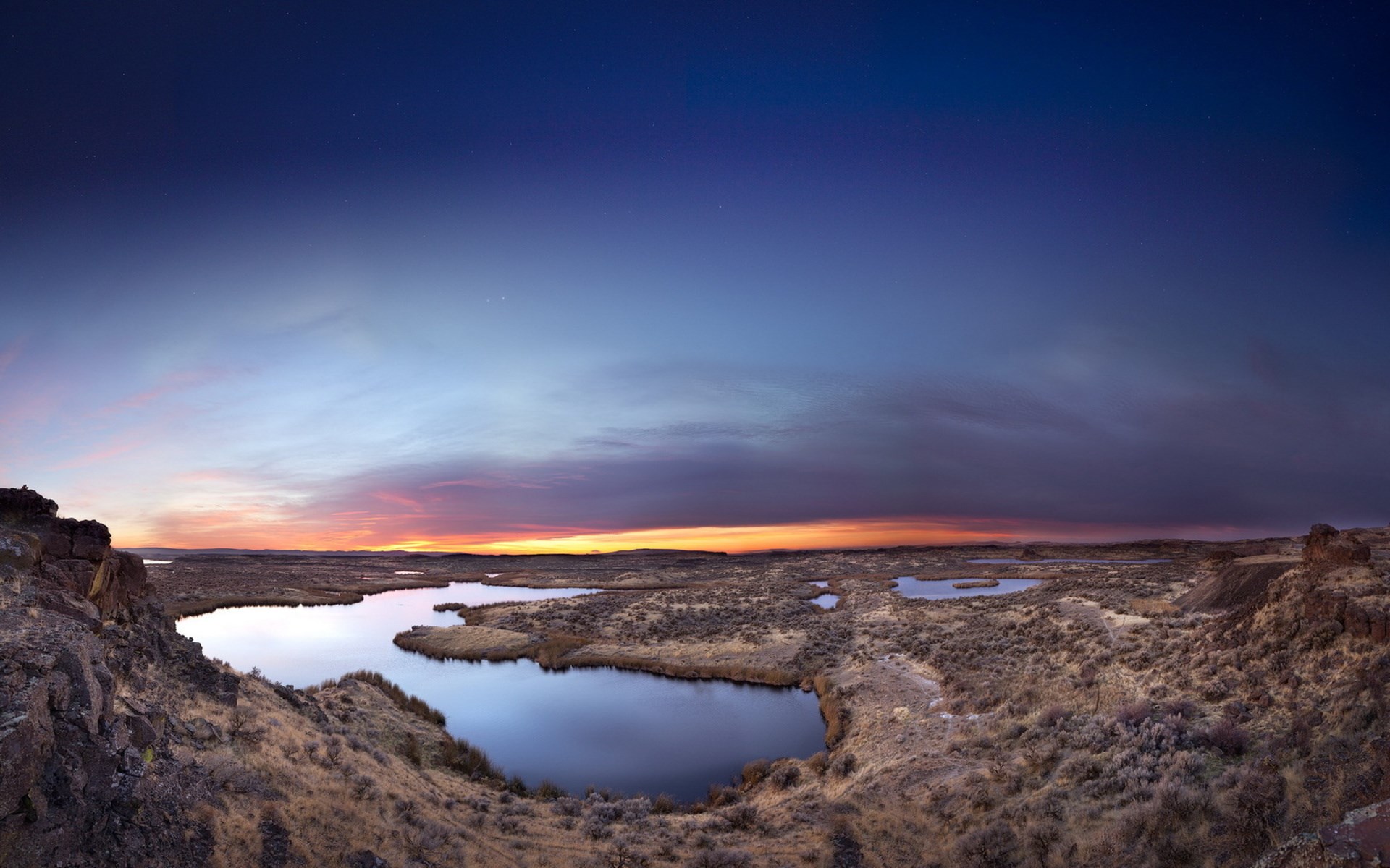 Panoramic view of a desert landscape with a lake at sunset HD Wallpaper
