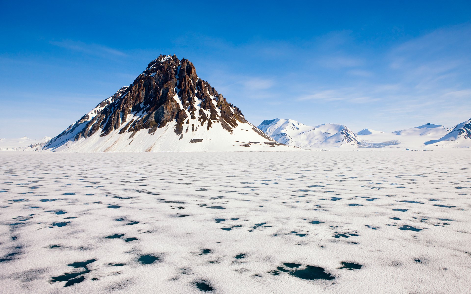 Snow-covered mountain range over icy landscape HD Wallpaper
