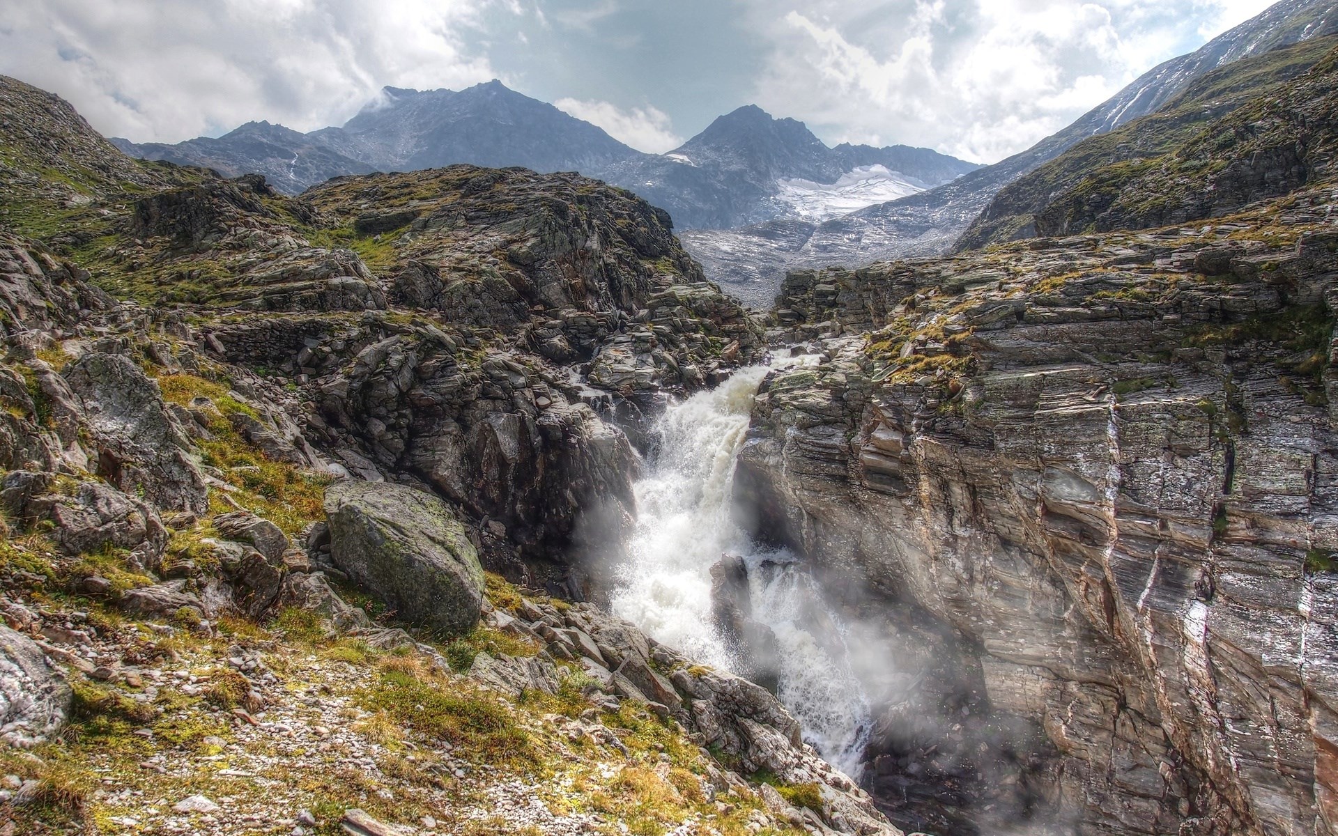Waterfall cascading through rocky mountain landscape HD Wallpaper