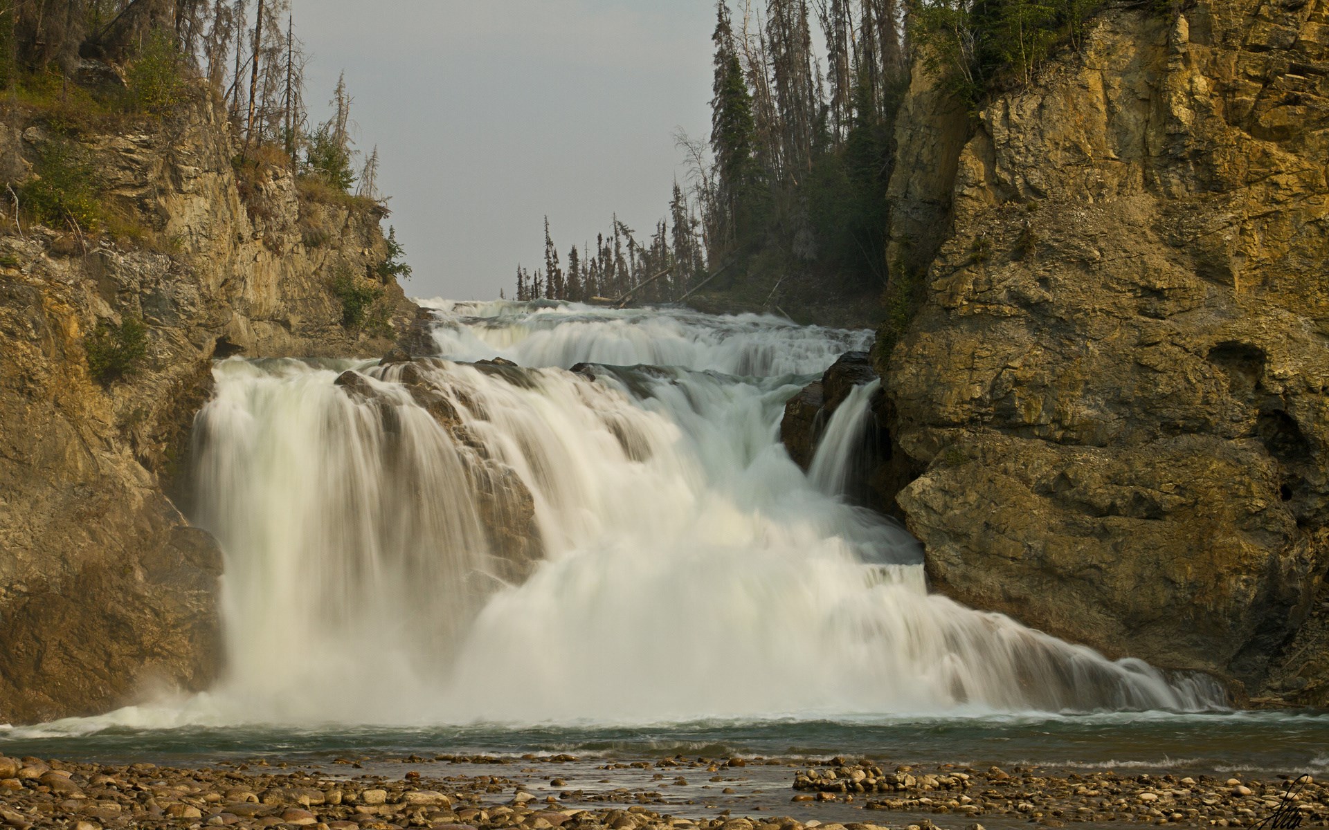 Waterfall cascading over rocks with trees HD Wallpaper