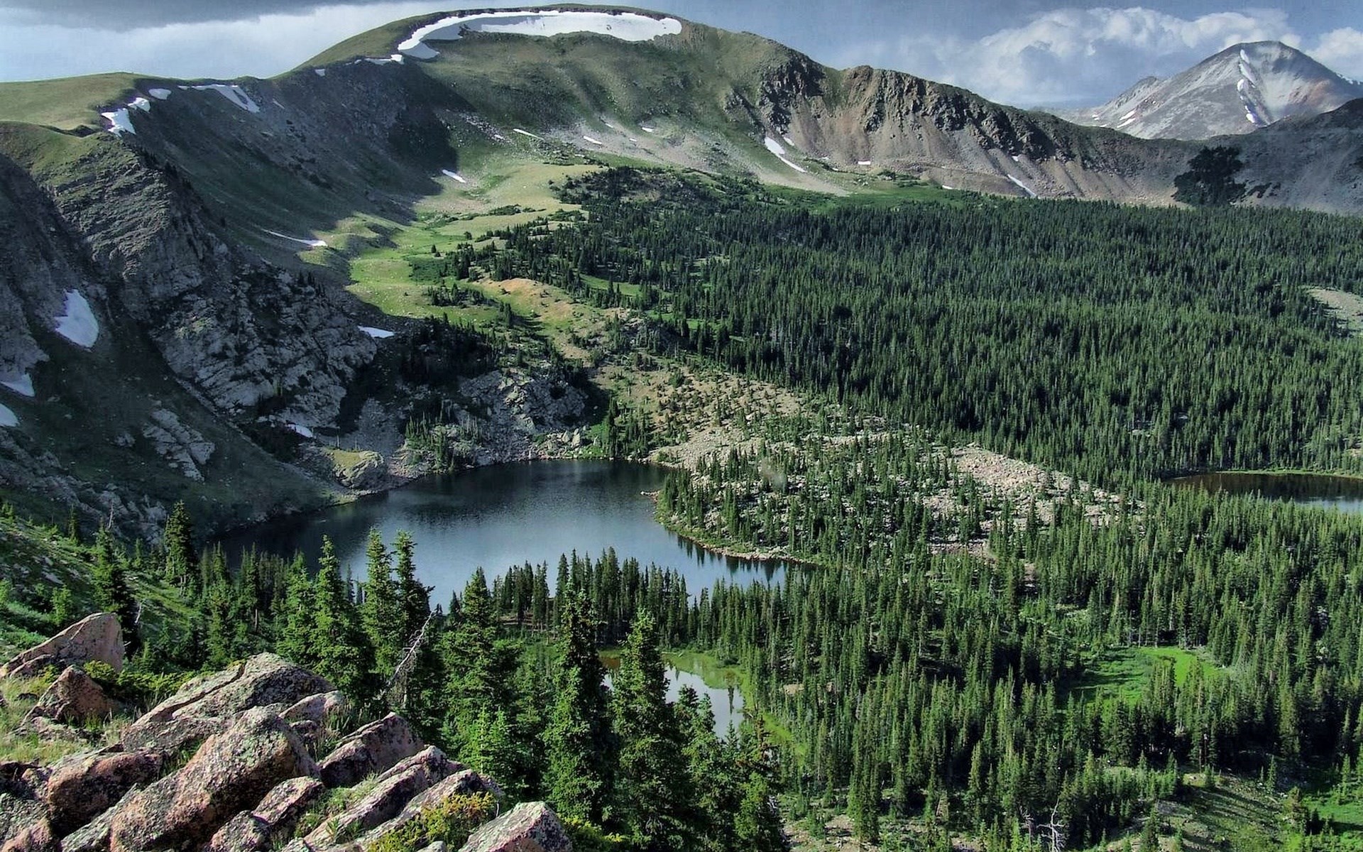Mountain lake surrounded by pine forest and rocky slopes HD Wallpaper
