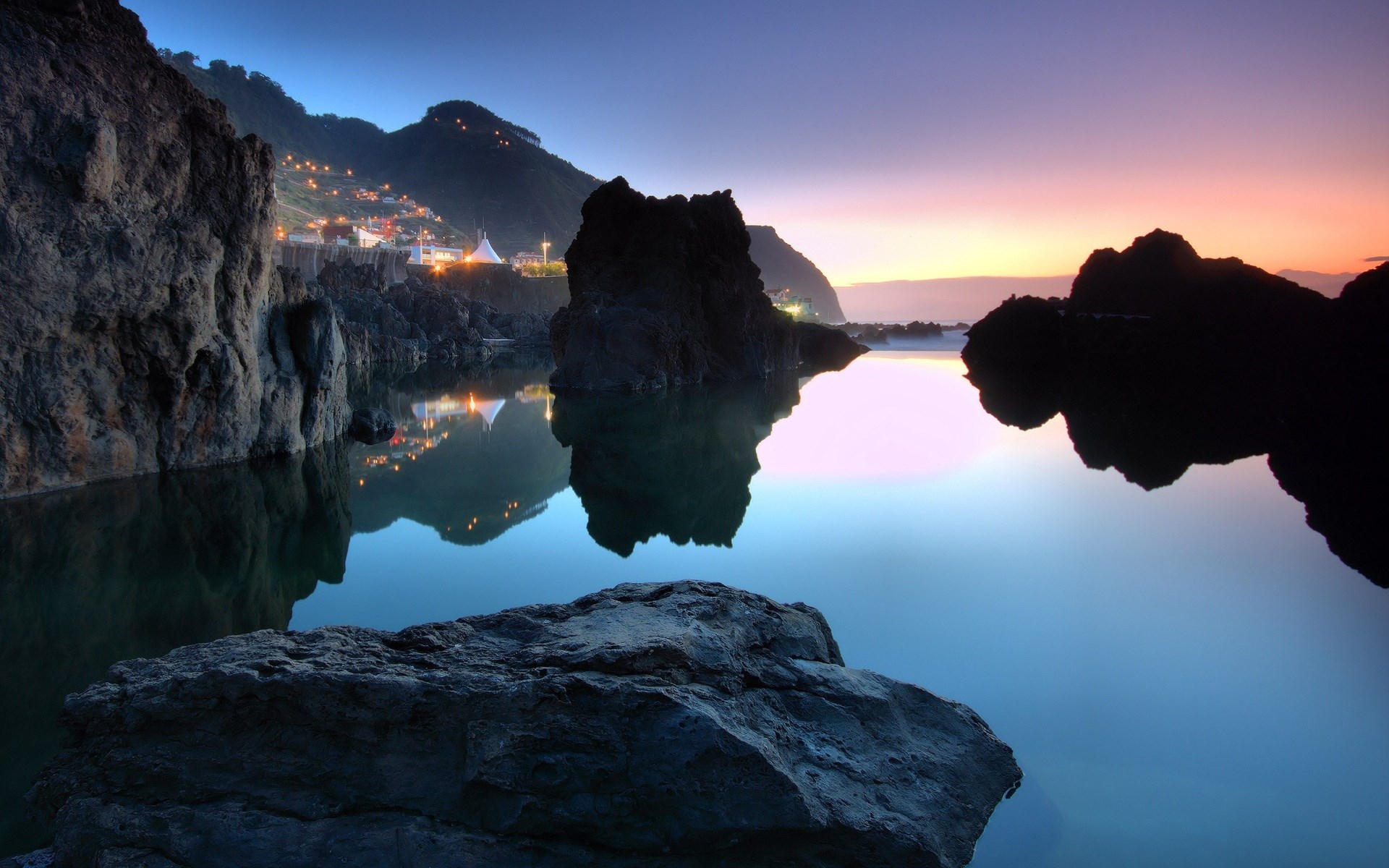 Coastal village at twilight reflected in calm water HD Wallpaper