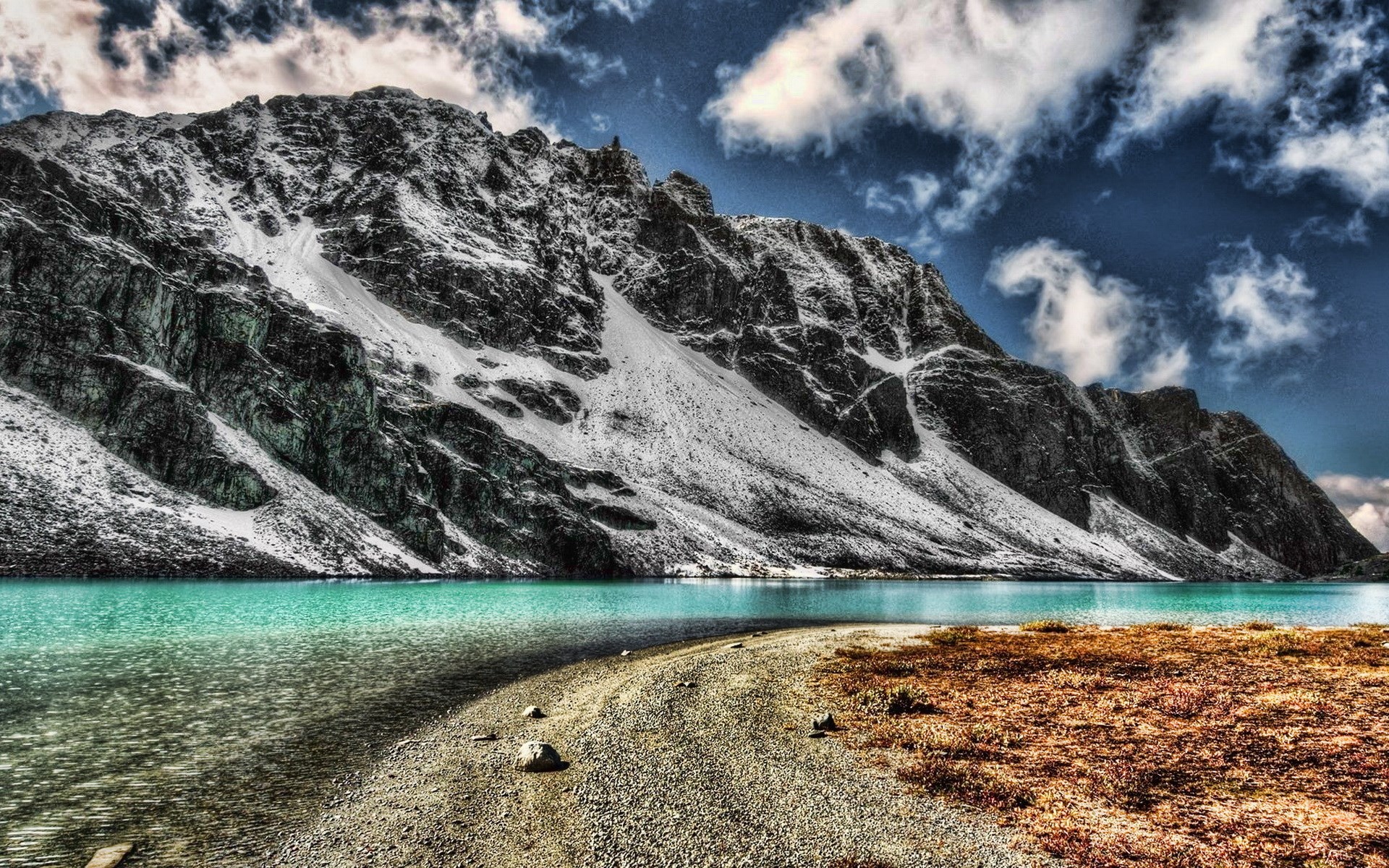 Turquoise lake at the base of a snow-dusted mountain HD Wallpaper