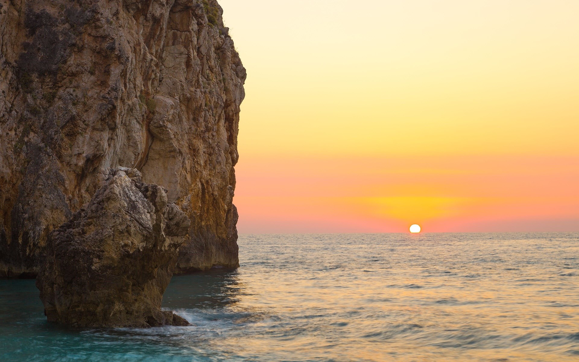 Sunset over the ocean with a rocky cliff HD Wallpaper